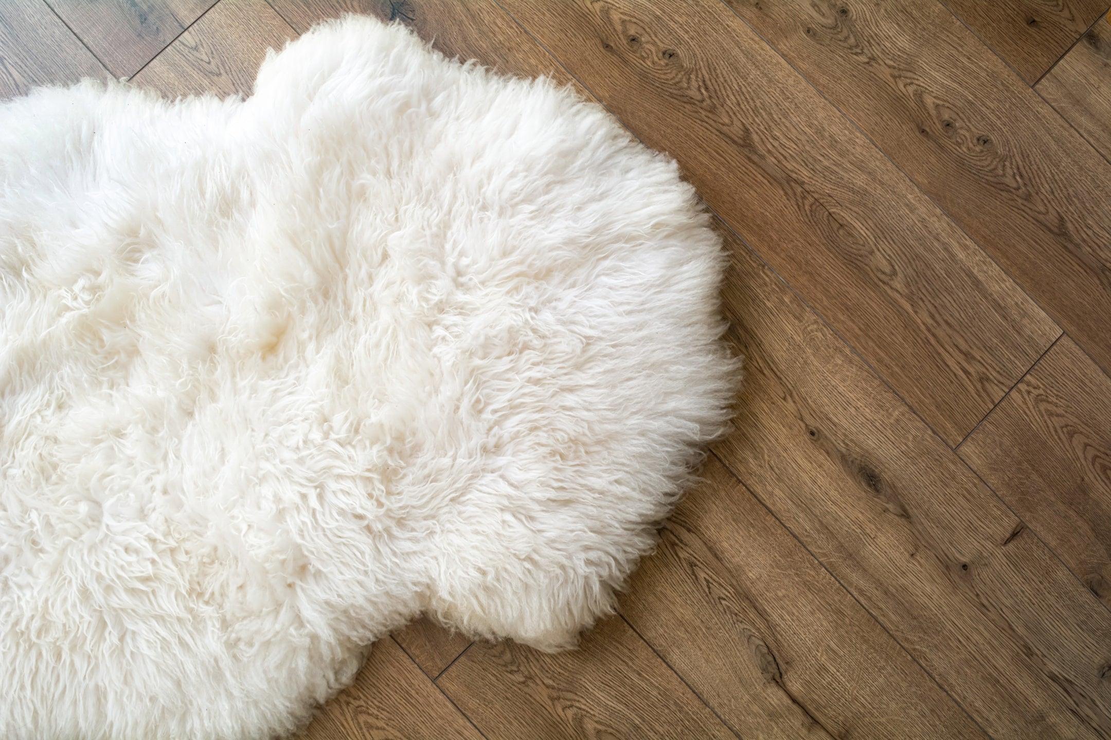 White sheepskin rug with soft wool texture on wooden floor