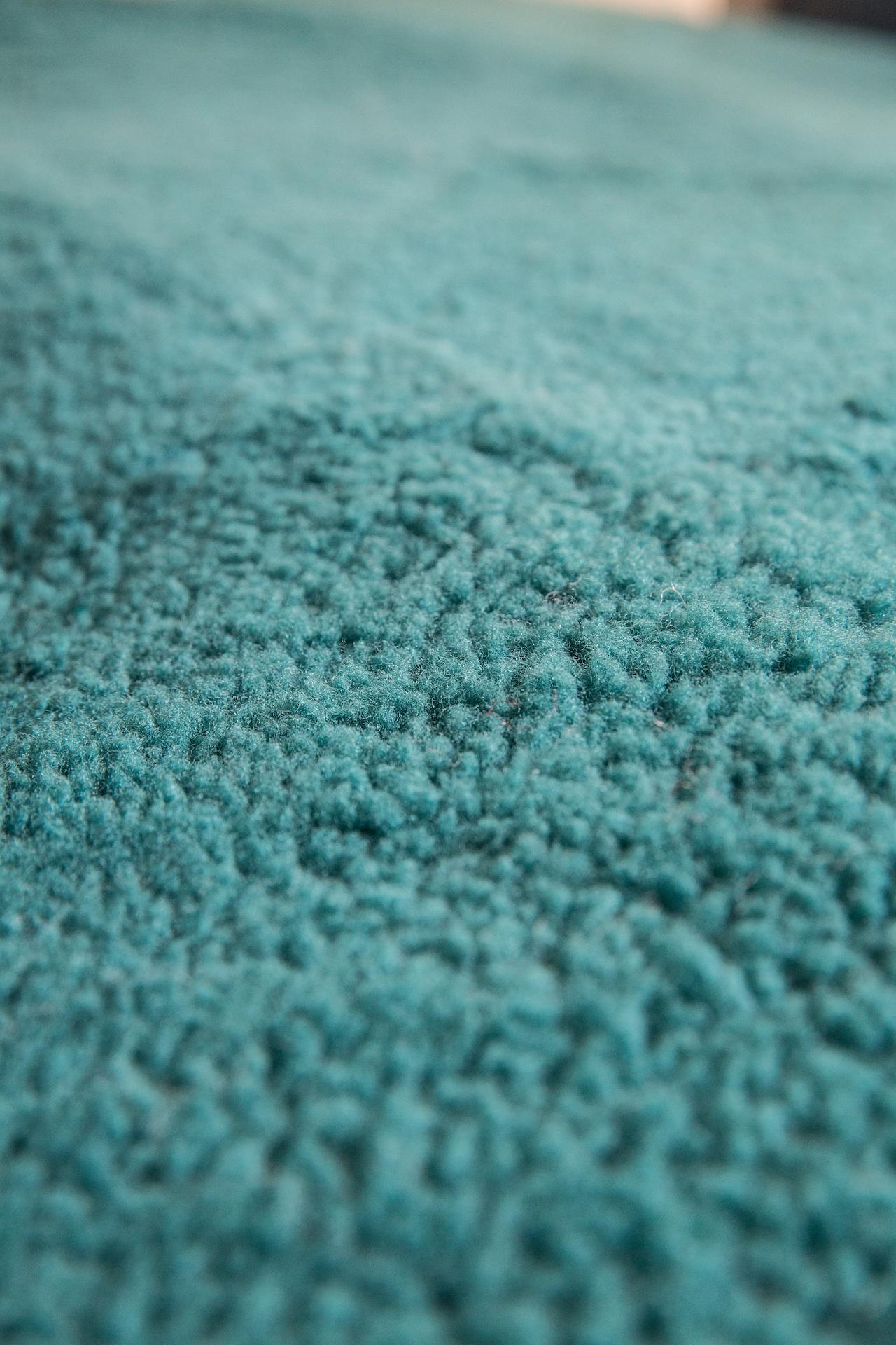 Close-up of teal sheepskin rug texture, soft wool pile, home decor textile