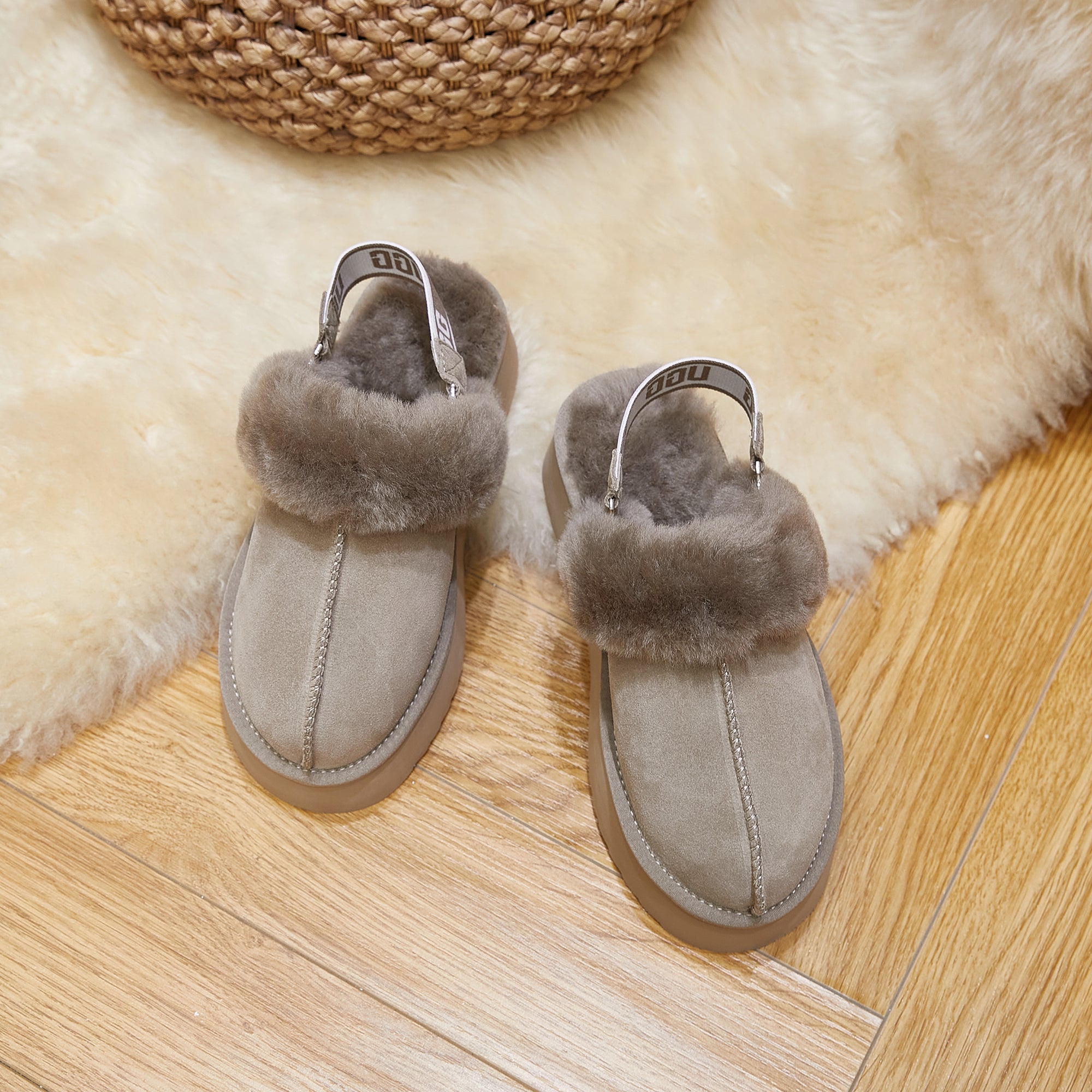 Beige sheepskin slippers with plush fur lining on a wool rug and wooden floor