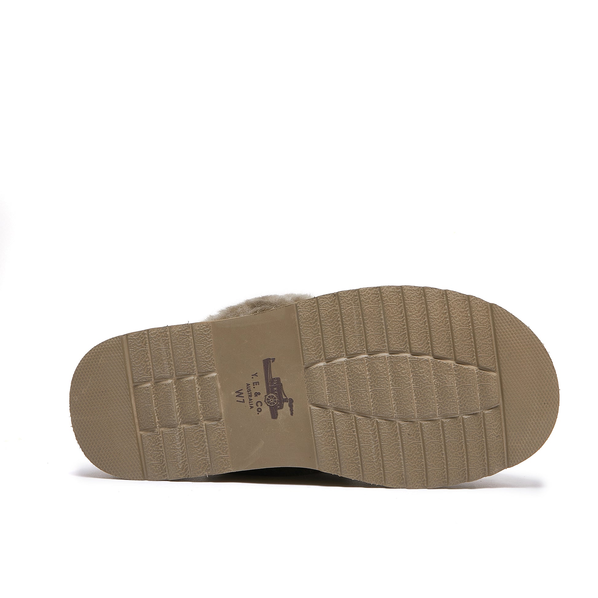 Textured sole of a beige sheepskin boot with visible logo and ribbed tread pattern