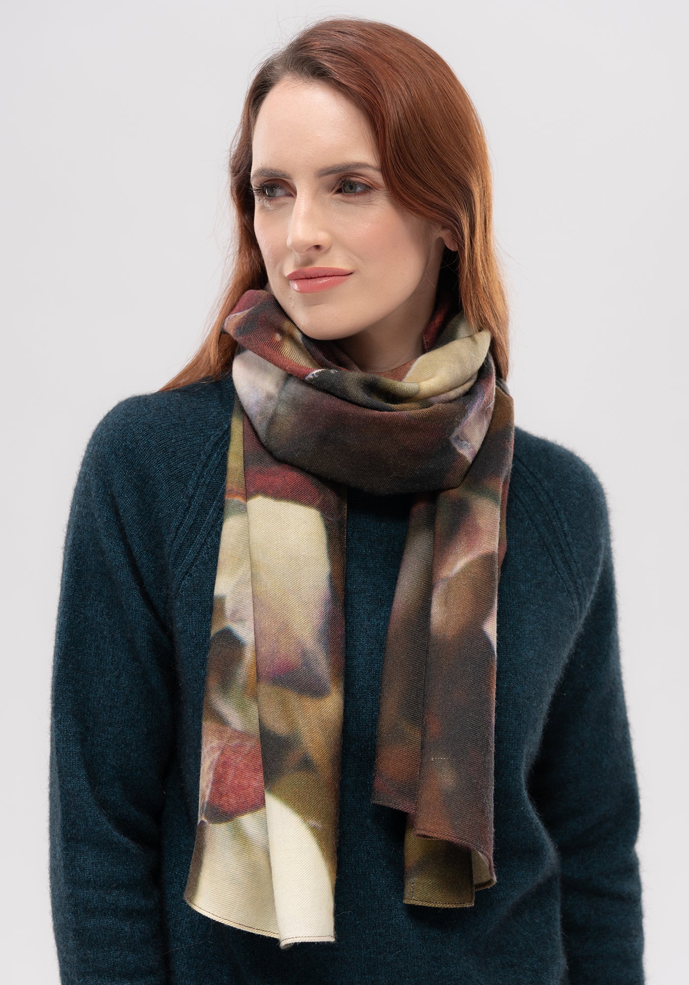 Woman wearing dark teal wool sweater with multicoloured plaid scarf in warm earth tones. - Yellow Earth Australia