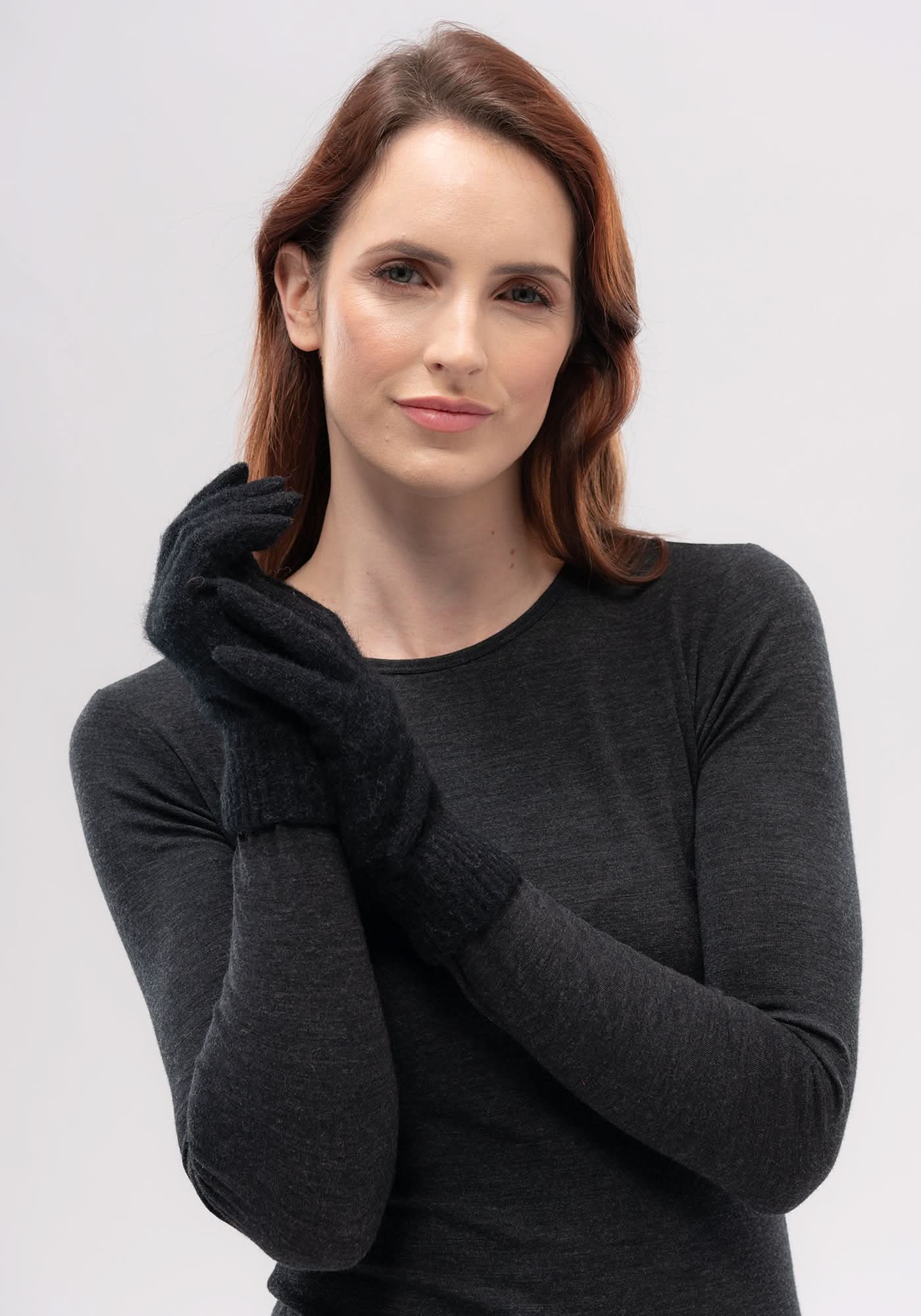 Woman wearing charcoal merino wool long-sleeve top with black gloves, front view. - Yellow Earth Australia