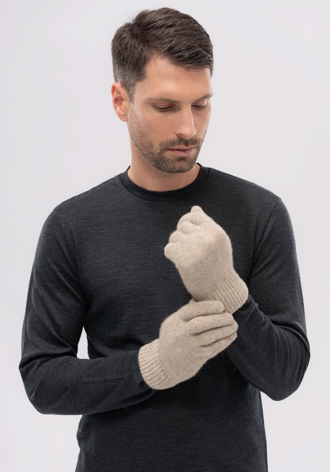 Cream wool mittens worn by man in charcoal sweater, front view. - Yellow Earth Australia