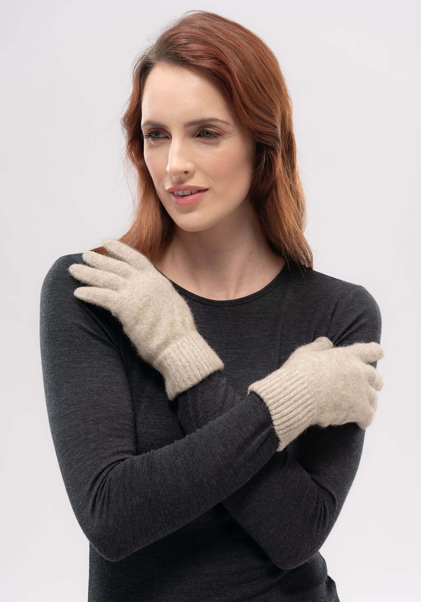 Cream wool gloves worn on charcoal sweater, front view against white background. - Yellow Earth Australia