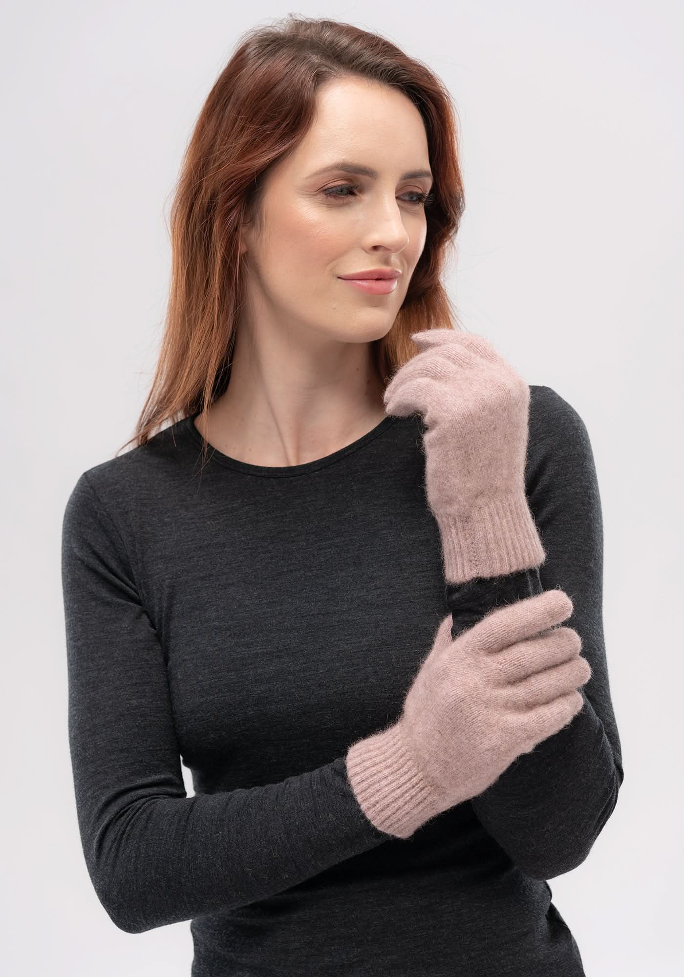 Woman wearing pink and black wool mittens with charcoal long-sleeve top, front view. - Yellow Earth Australia