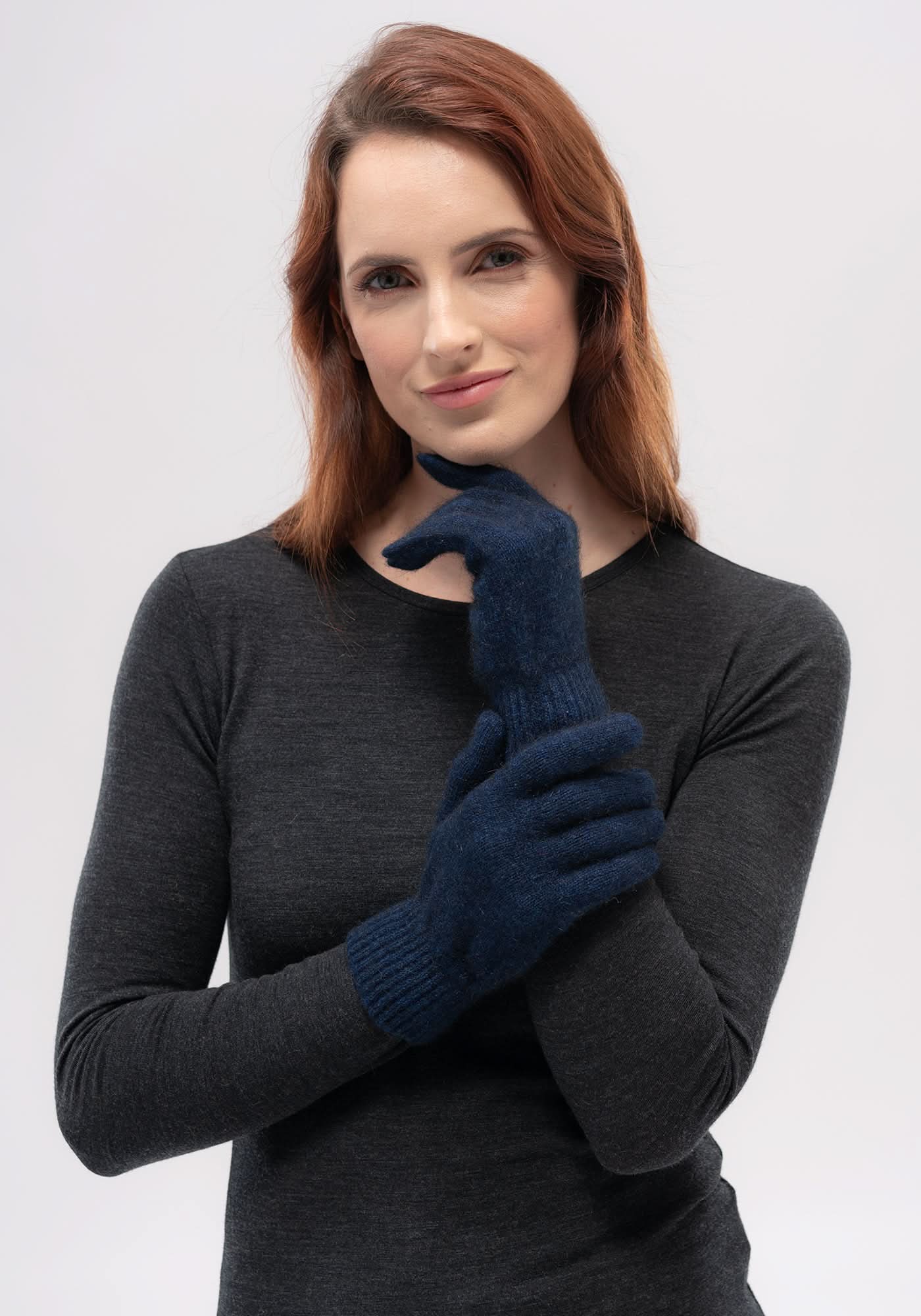 Woman wearing navy blue wool knit gloves with charcoal long-sleeve top, front view. - Yellow Earth Australia