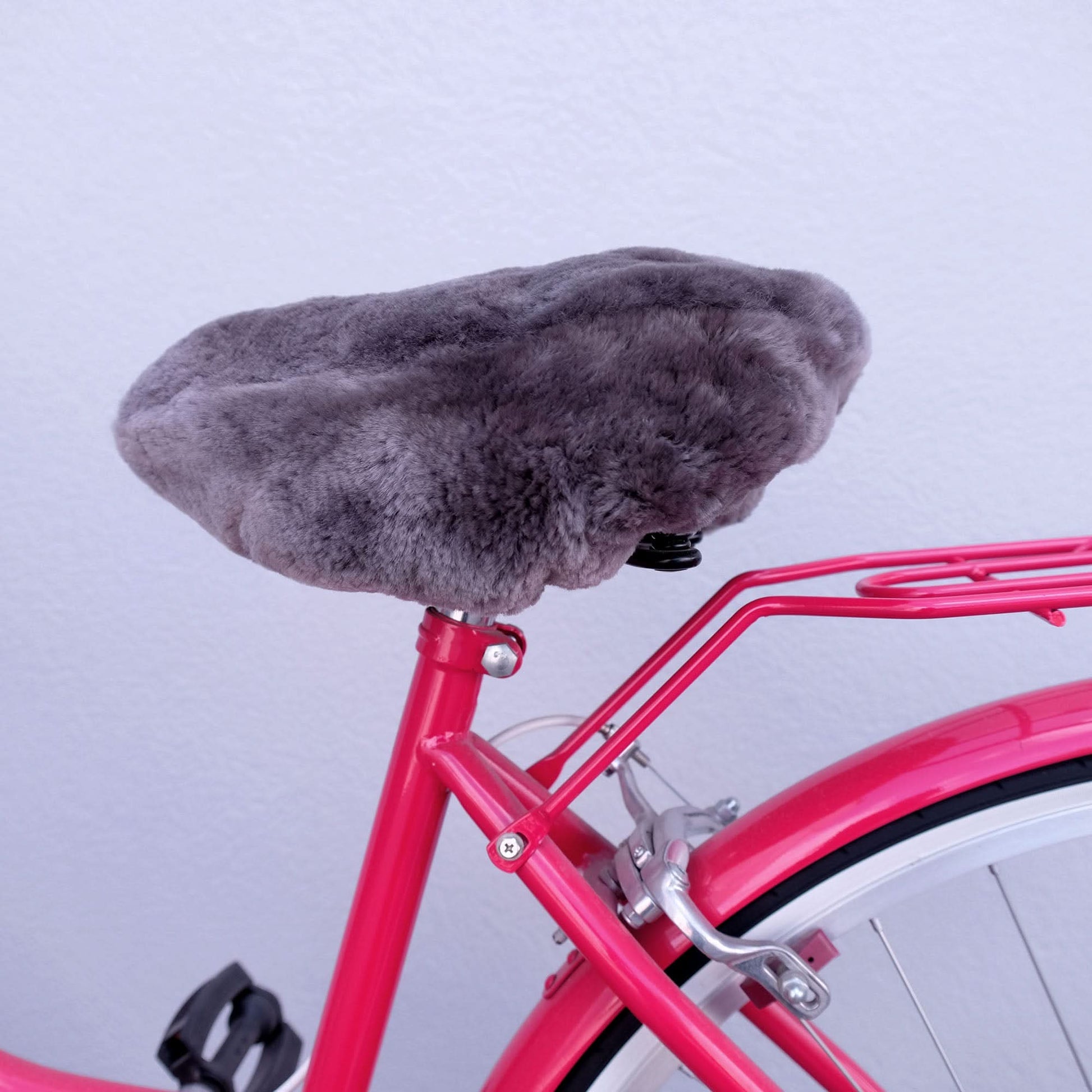 Grey sheepskin bicycle seat cover on bright pink bike frame, overhead view. - Yellow Earth Australia