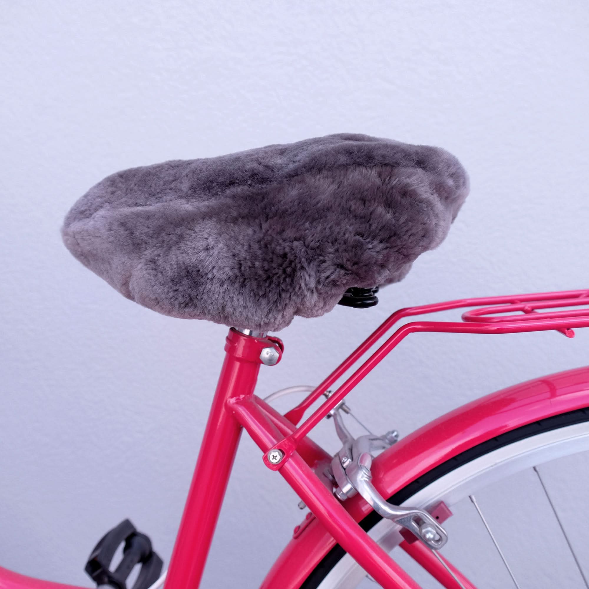 Grey sheepskin bicycle seat cover on bright pink bike frame, overhead view. - Yellow Earth Australia