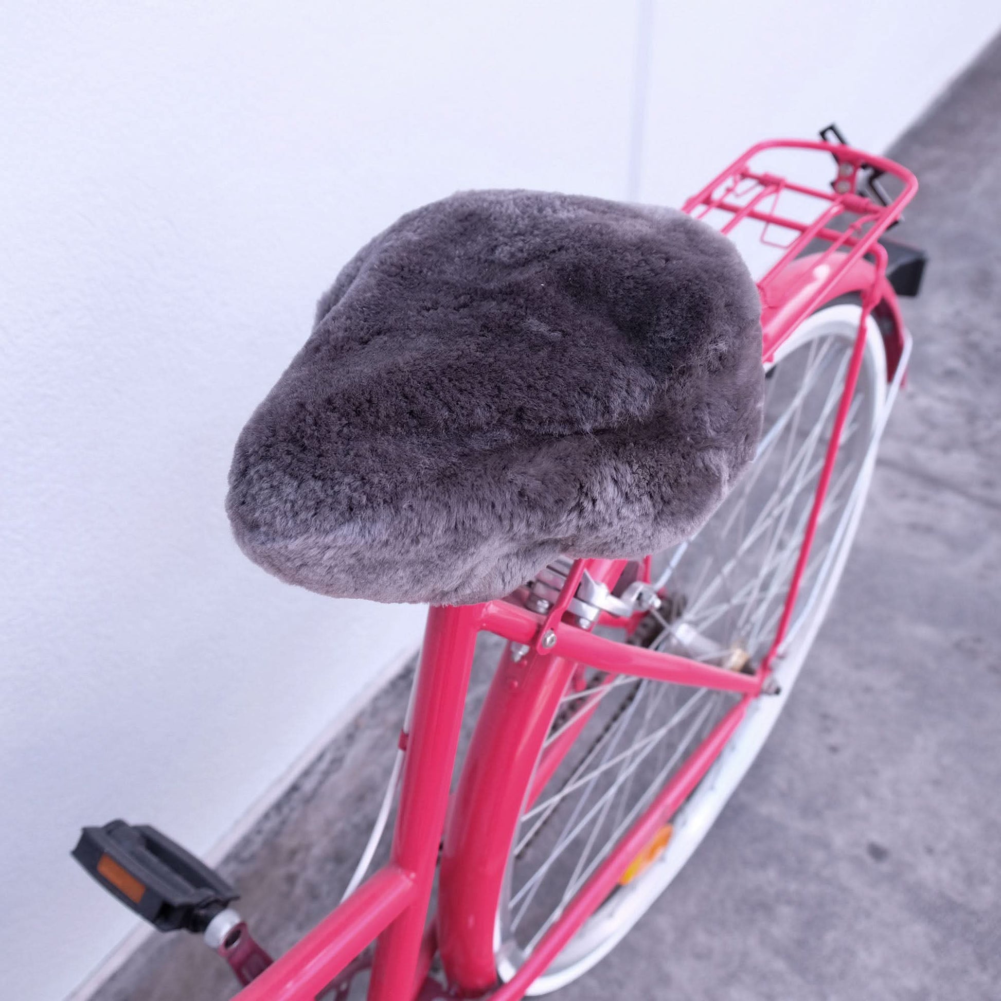 Grey sheepskin bicycle seat cover on pink bike shown from above angle. - Yellow Earth Australia