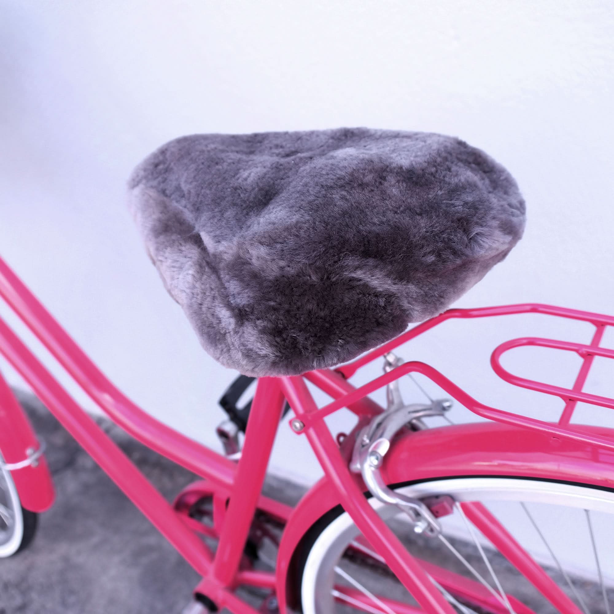 Gray sheepskin bicycle seat cover on bright pink bike frame, top view. - Yellow Earth Australia