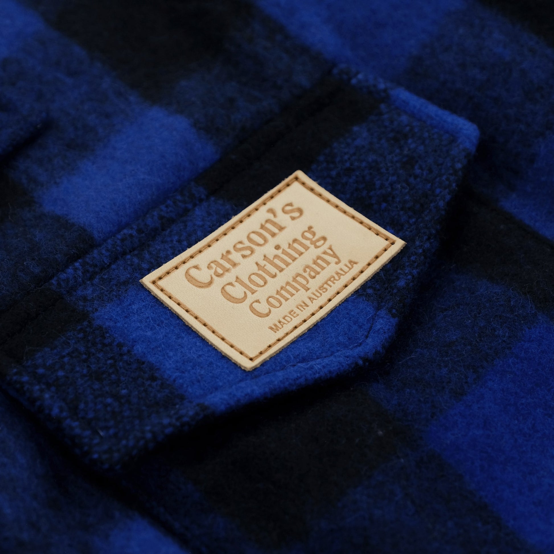 Blue and black checkered wool clothing label on fabric close-up detail. - Yellow Earth Australia