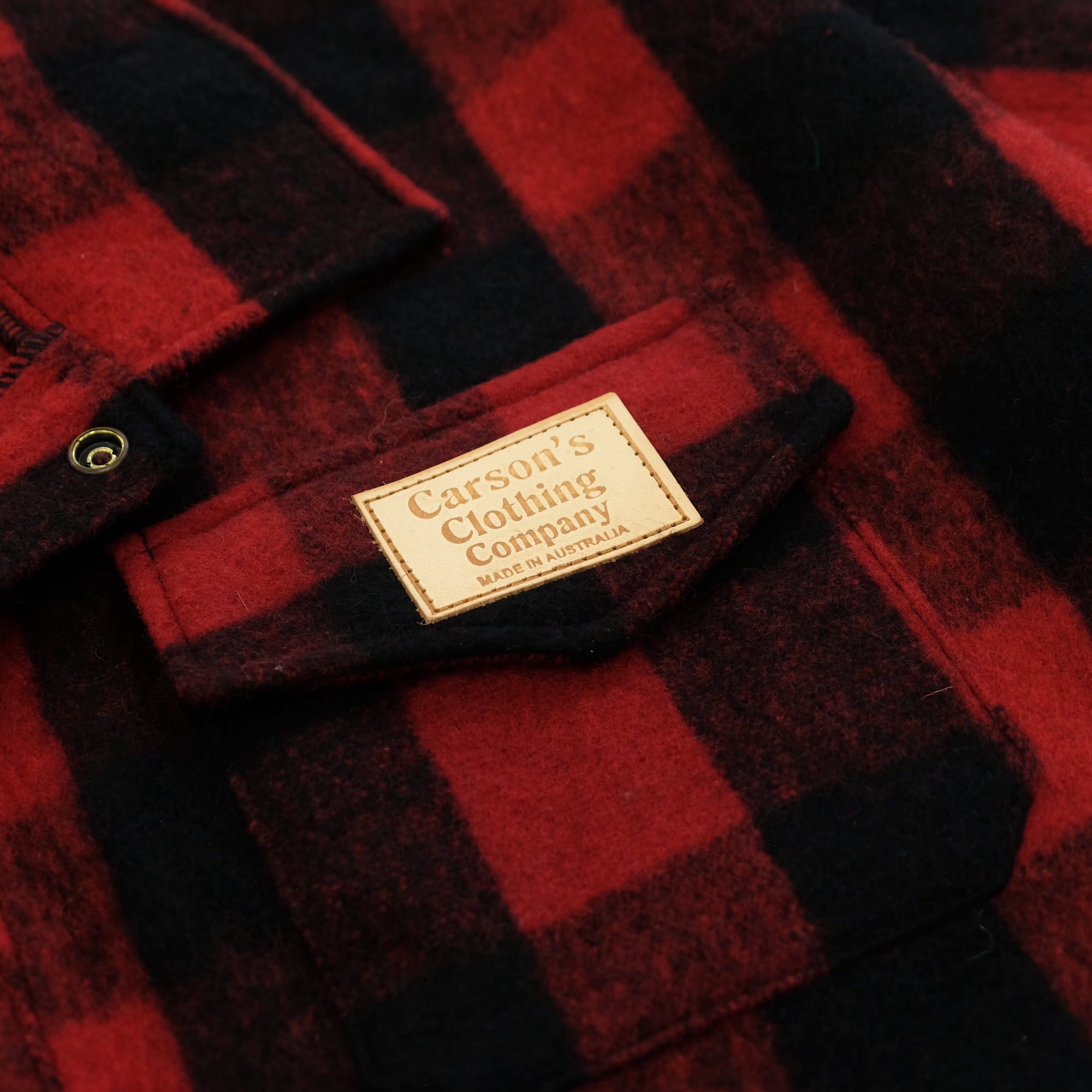 Red and black checked wool shirt laid flat showing fabric texture and care label. - Yellow Earth Australia