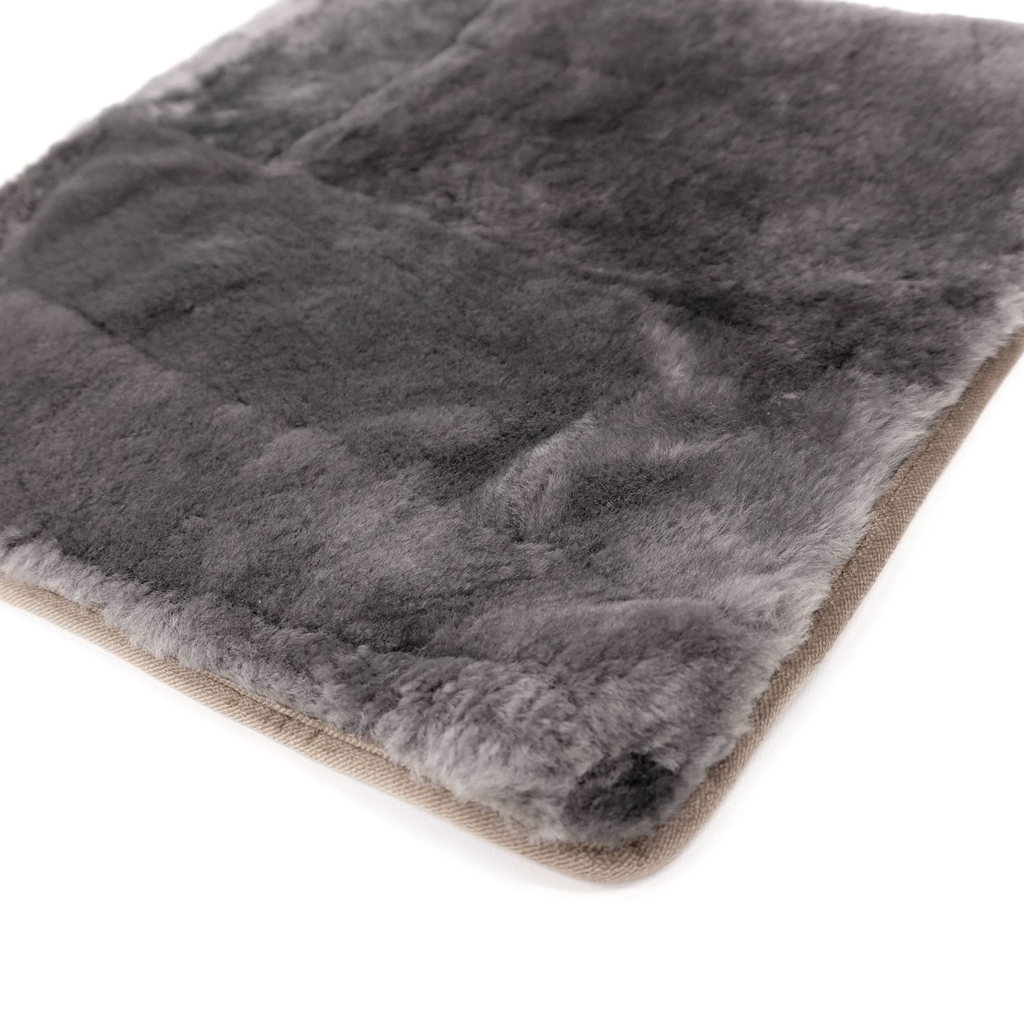 Grey sheepskin rug with natural wool pile and beige backing, angled view. - Yellow Earth Australia