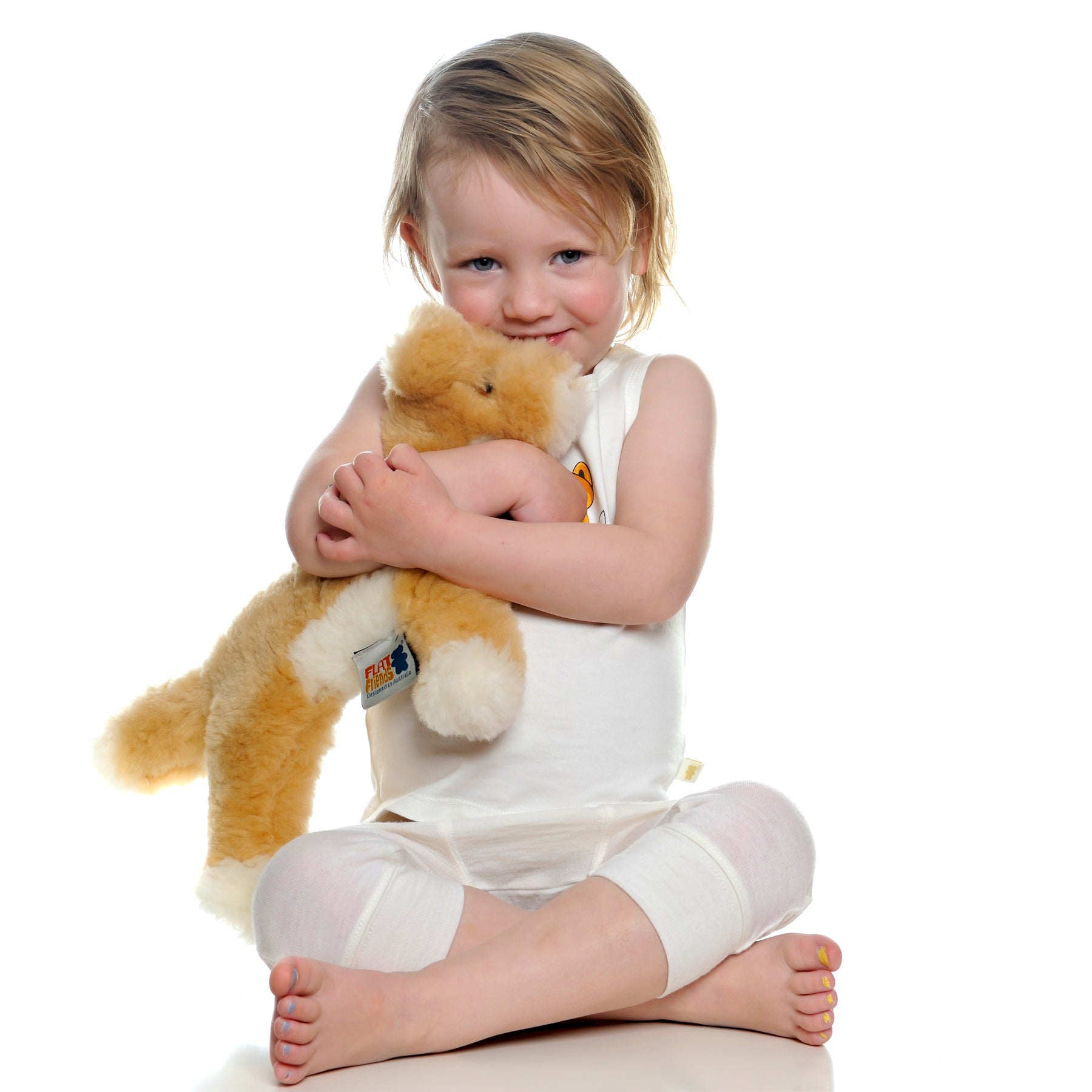 Toddler hugging golden sheepskin teddy bear with cream wool belly, front view. - Yellow Earth Australia