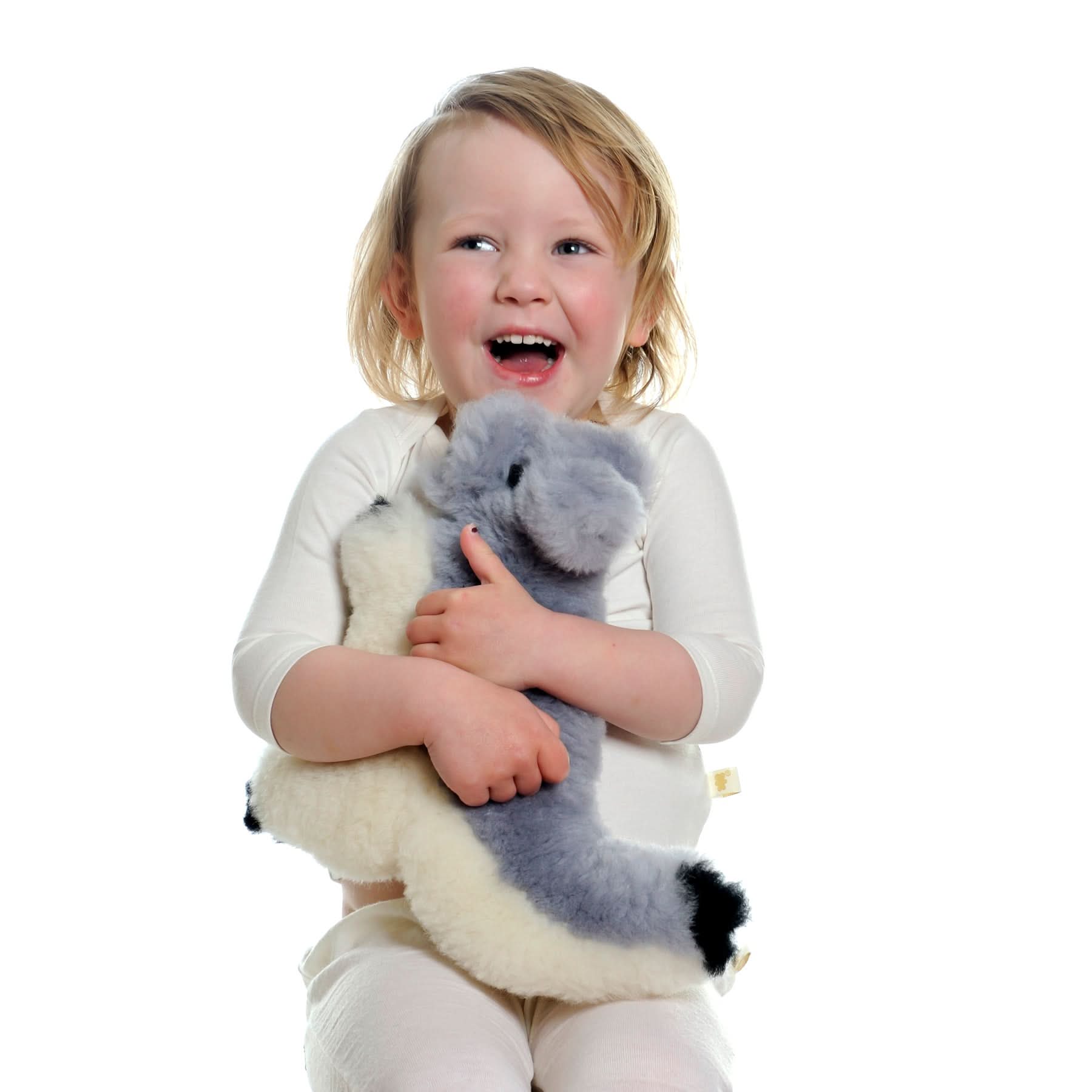 Toddler holding grey and white sheepskin toy with soft wool texture against white background. - Yellow Earth Australia