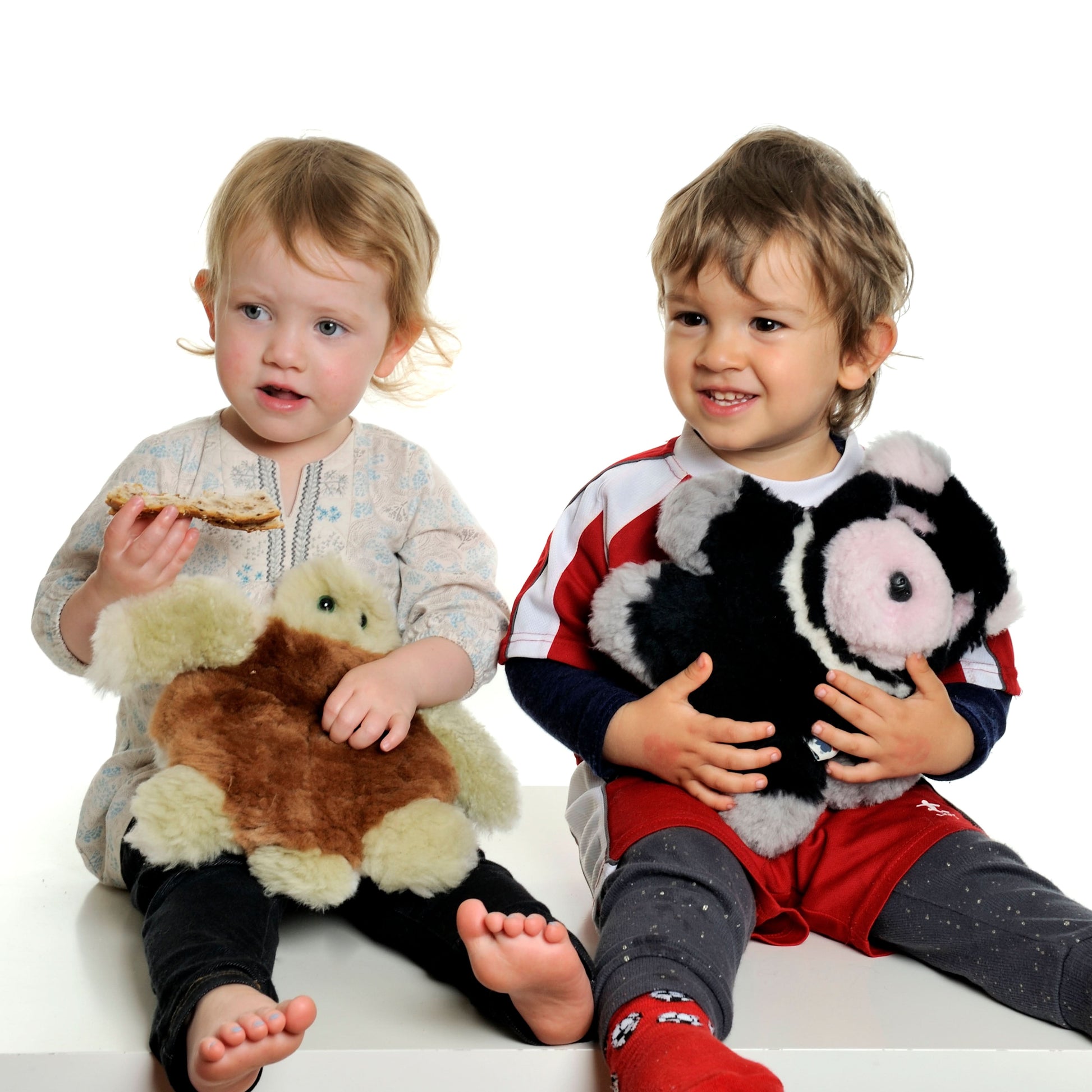 Two toddlers holding soft plush animal toys made from wool and sheepskin material. - Yellow Earth Australia