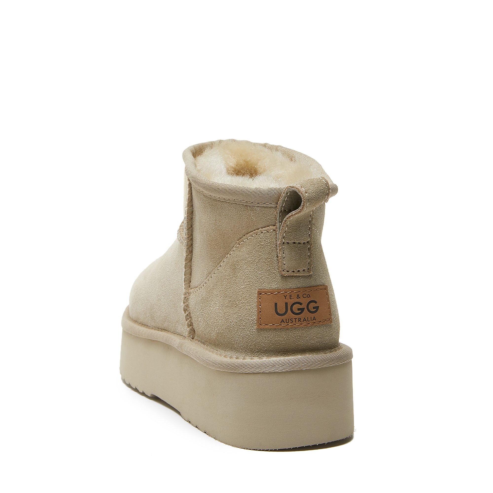 Beige sheepskin UGG boot with plush lining and platform sole, rear view on white background.