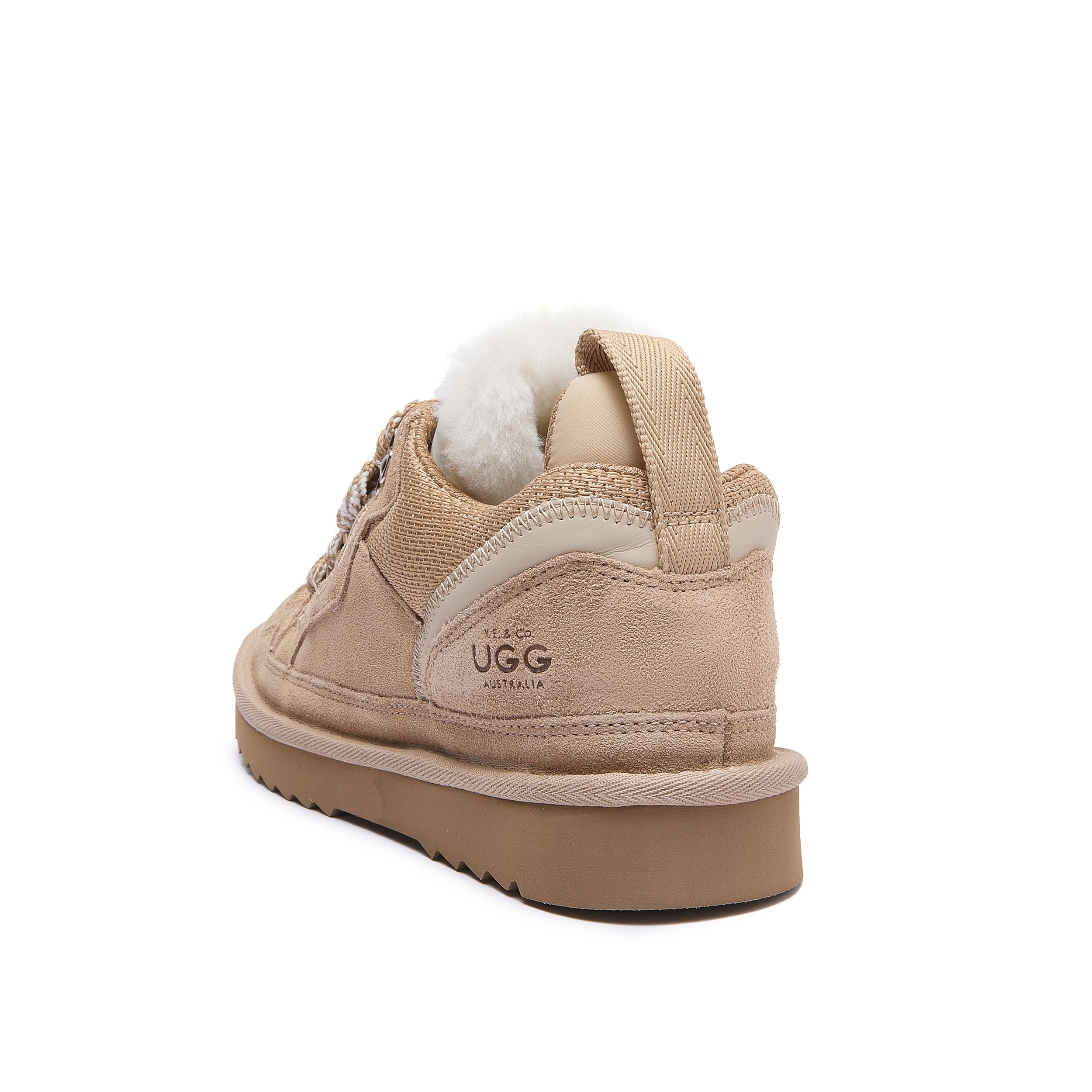 Leslie Chunky Sheepskin-Lined Sneaker in Sand - A beige Ugg low-top sneaker with a white shearling lining visible at the collar, shown from a rear three-quarter angle on a white background.