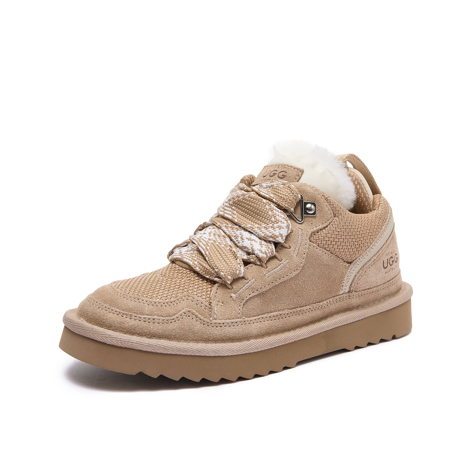 Leslie Chunky Sheepskin-Lined Sneaker in Sand - A beige low-top sneaker with a fuzzy white lining, chunky tan sole, and decorative braided laces, shown from a three-quarters angle on a white background.