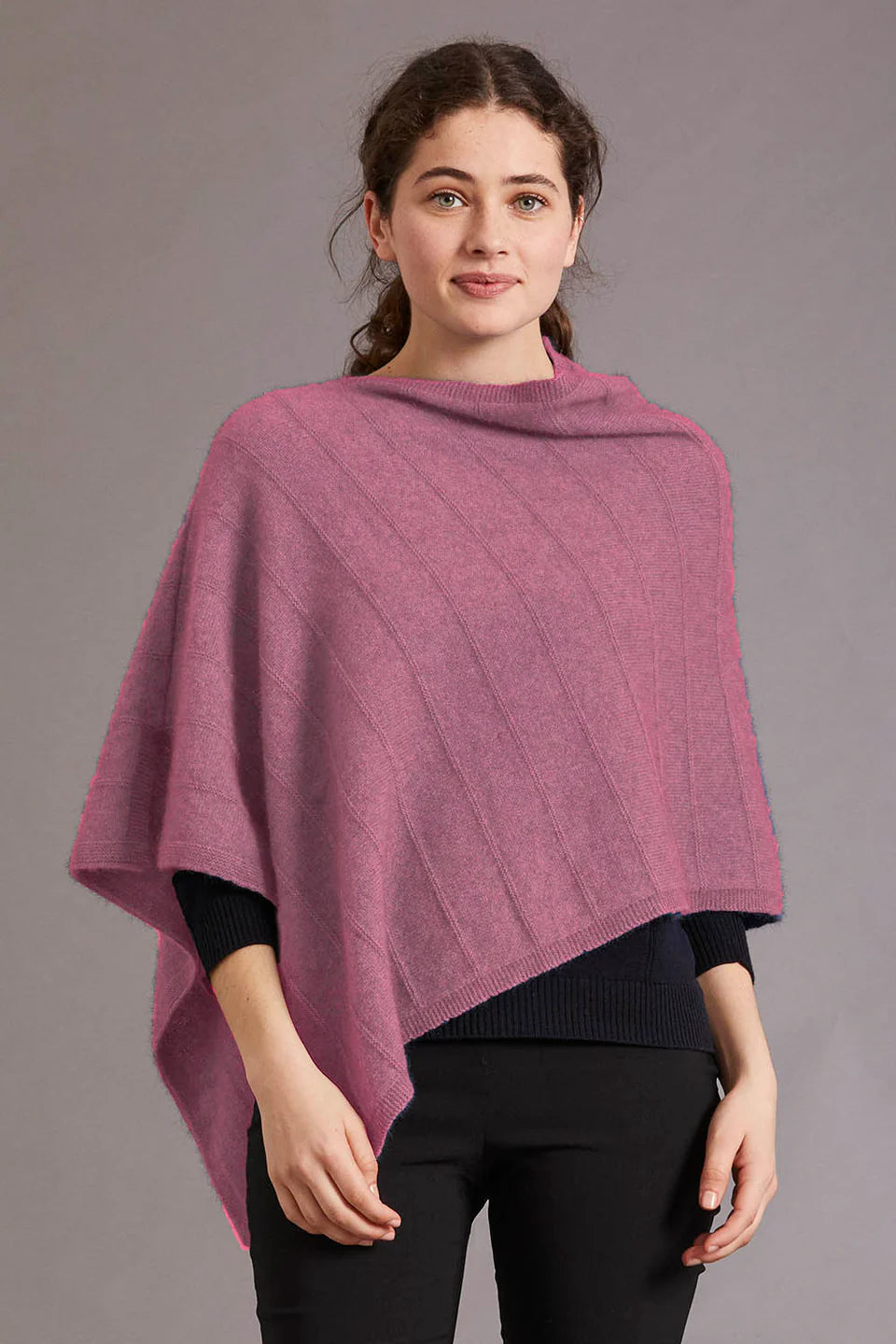 Woman wearing mauve wool poncho over black ribbed top, front view against grey background. - Yellow Earth Australia