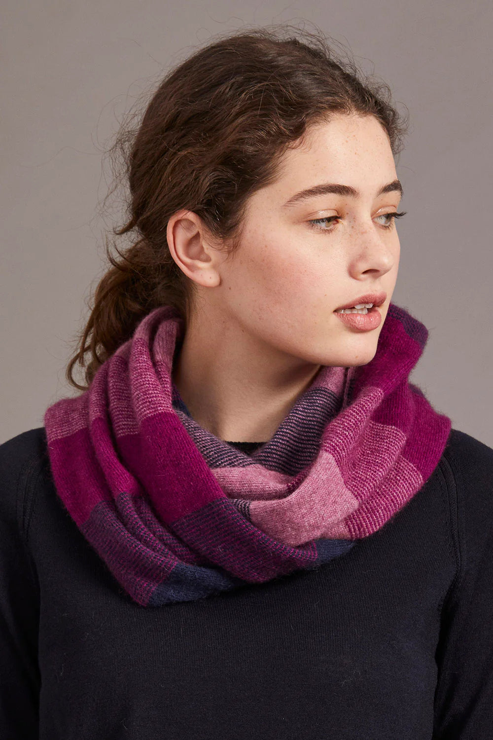 Woman wearing purple checked wool cowl neck scarf over black sweater, side view. - Yellow Earth Australia