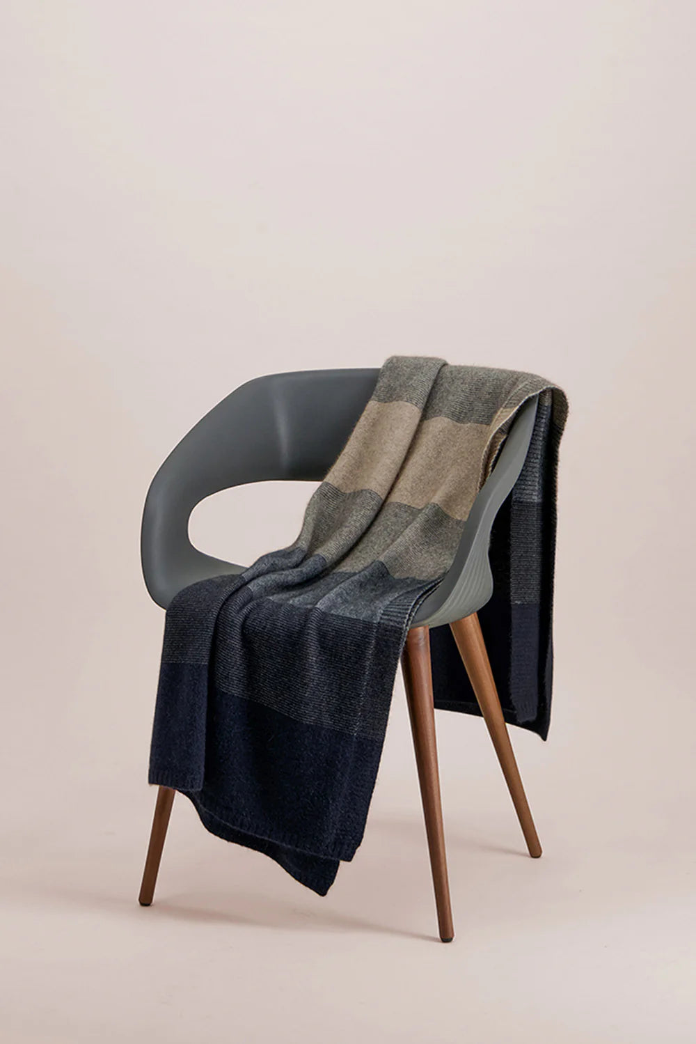Striped wool throw blanket draped over modern grey chair with wooden legs. - Yellow Earth Australia