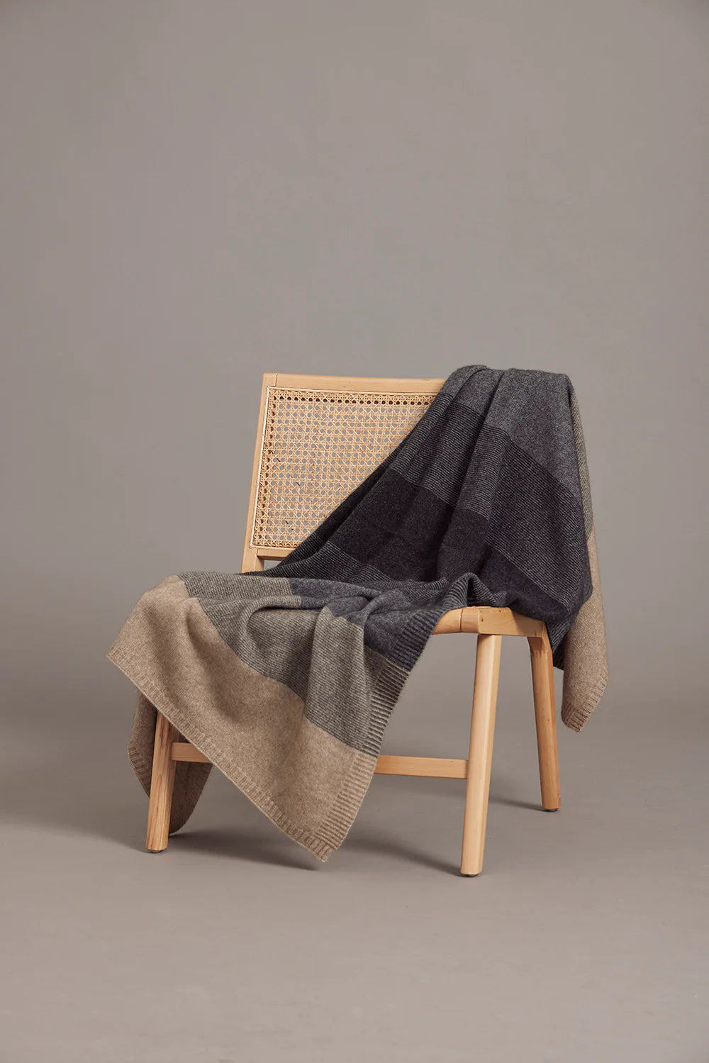 Natural wood chair draped with charcoal and beige wool throw blanket. - Yellow Earth Australia