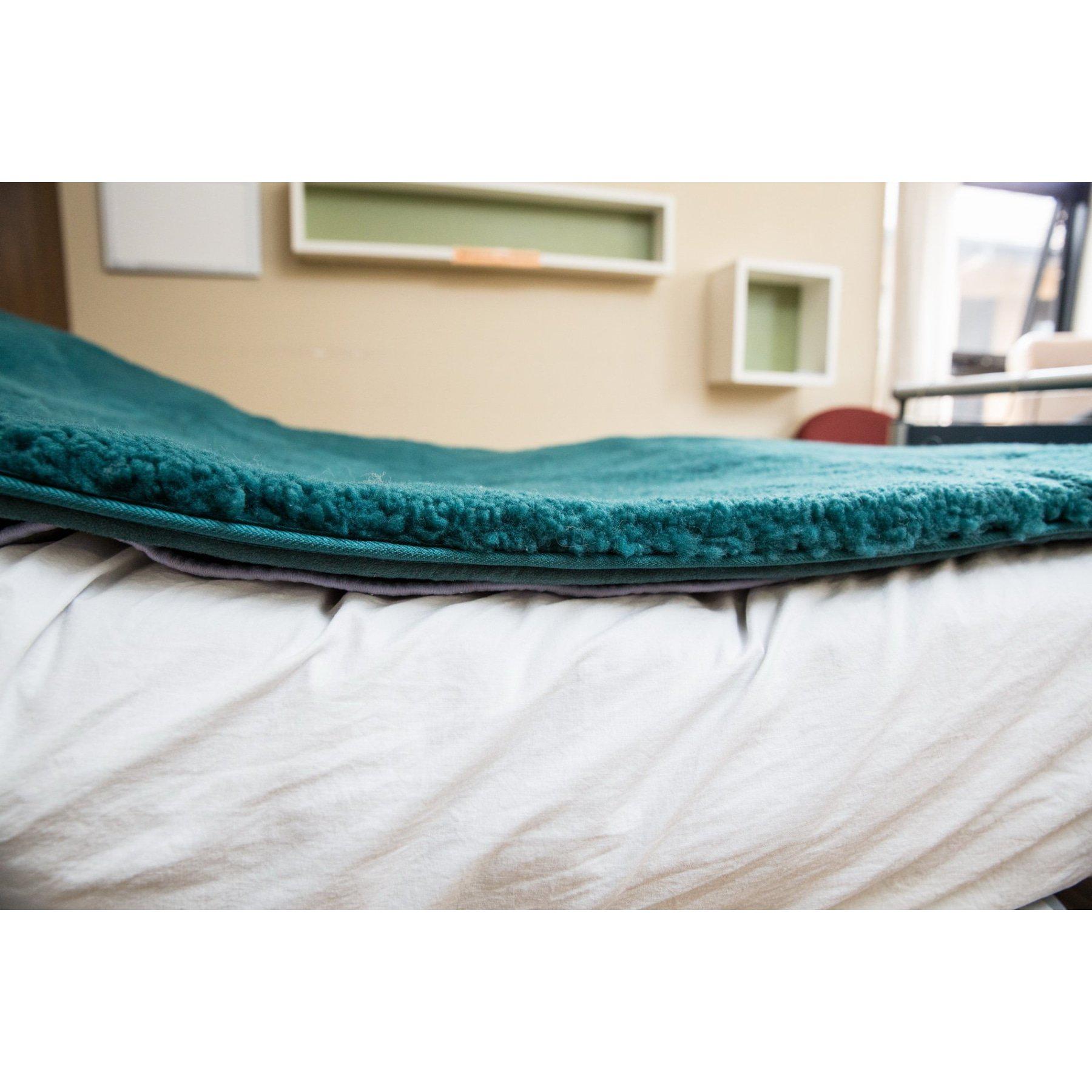 Teal wool blanket layered over cream sheepskin rug, side profile view. - Yellow Earth Australia