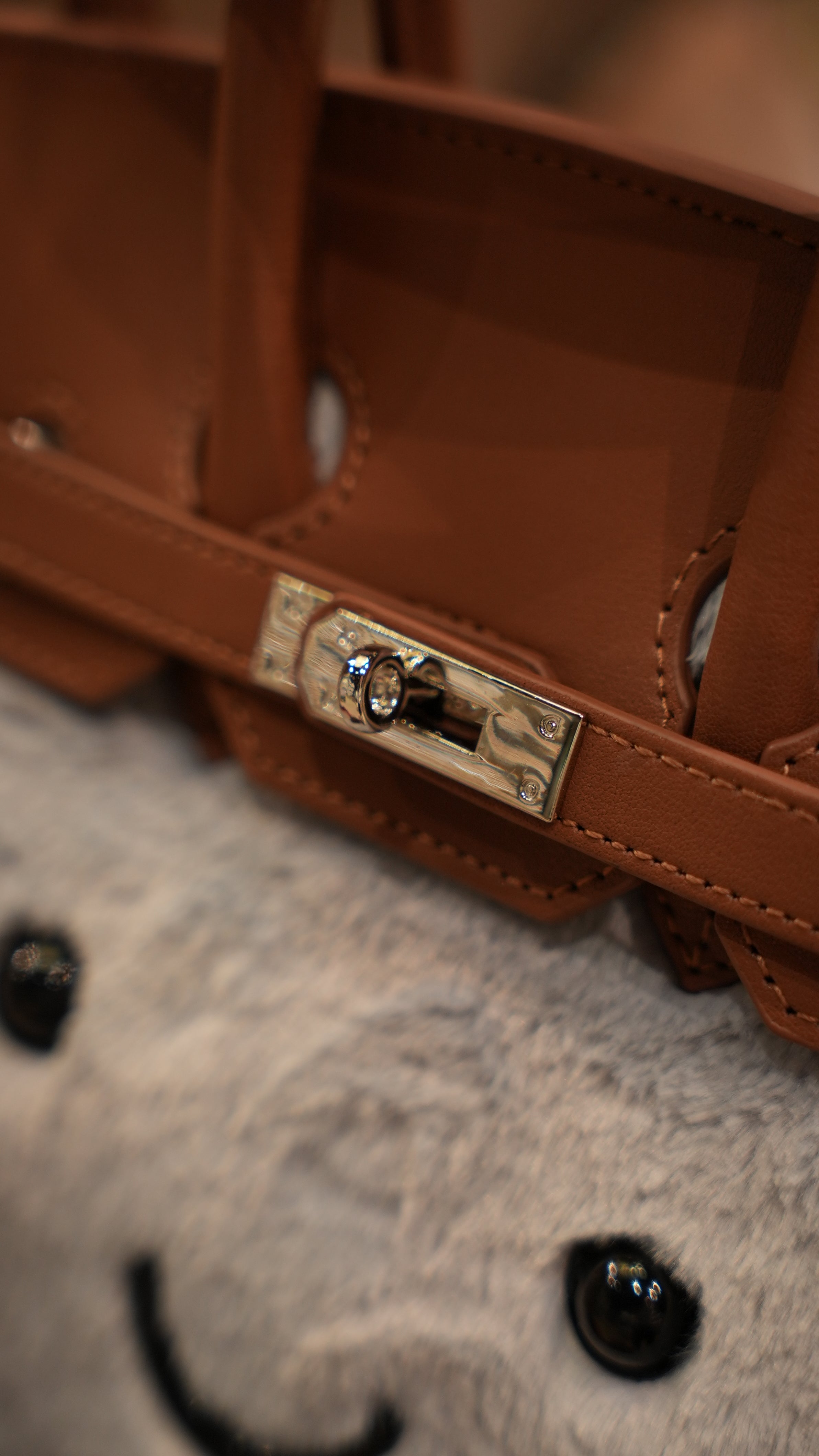 Brown leather satchel with metal clasp detail on cream sheepskin fabric surface. - Yellow Earth Australia