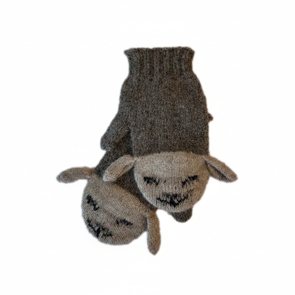 A pair of mittens shaped like sheep heads, featuring a dark brown knit body and a light beige knit face with black embroidered eyes and mouth details, shown against a plain white background.