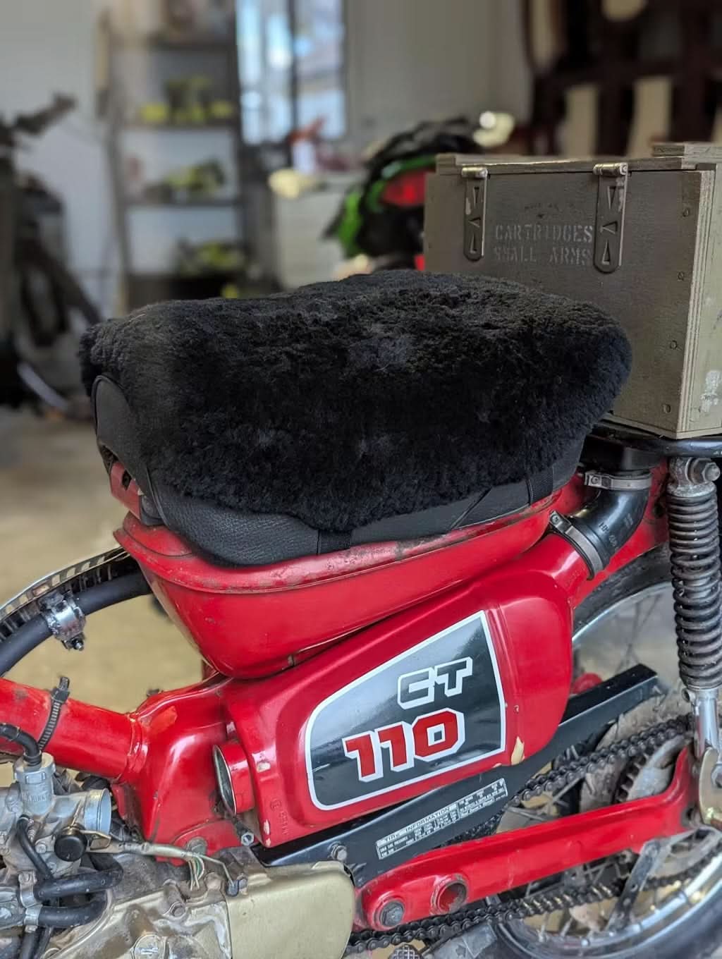 Black sheepskin motorcycle seat cover on red vintage motorbike, top view. - Yellow Earth Australia
