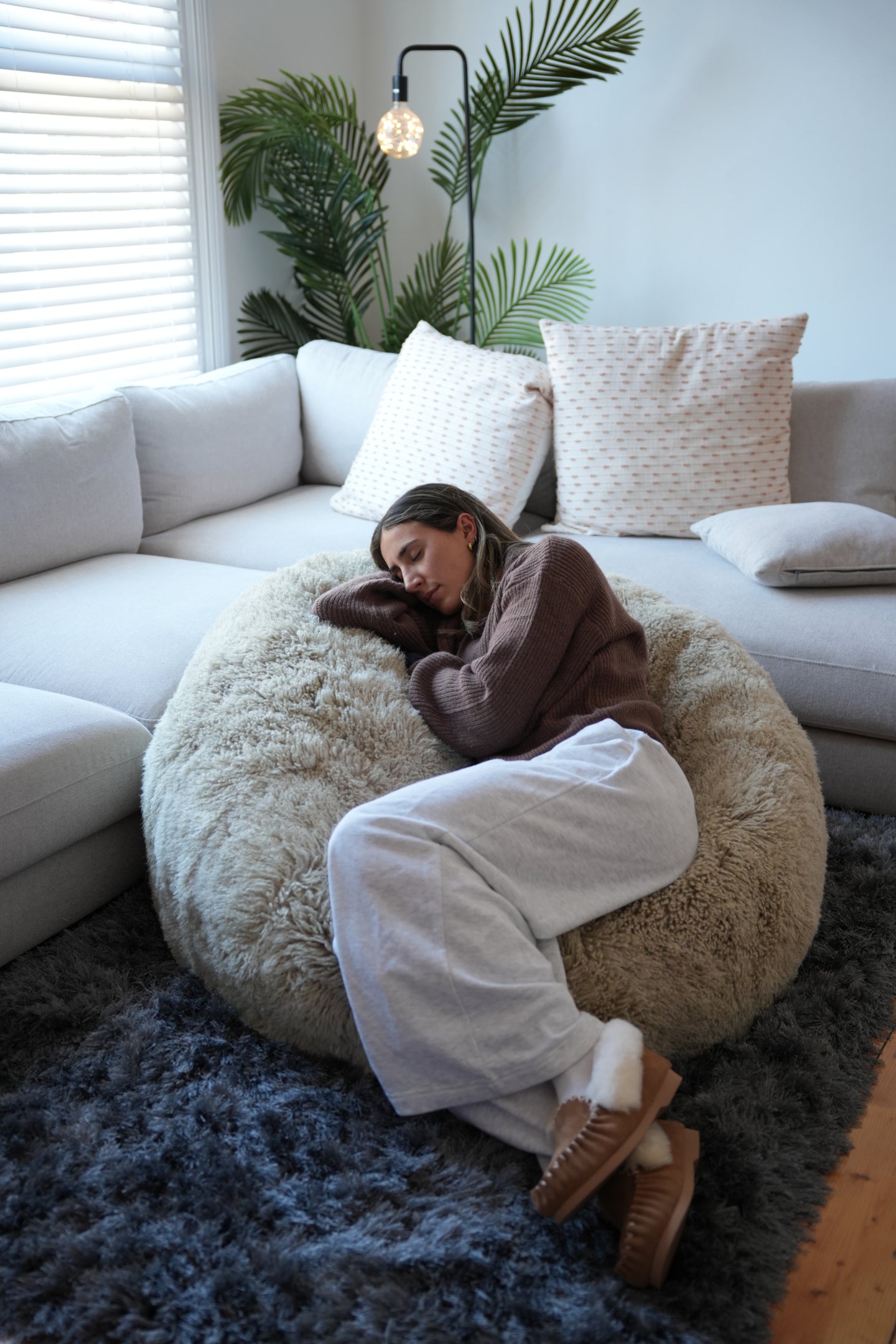 Cream sheepskin bean bag chair with woman sitting, showing plush wool texture and comfort. - Yellow Earth Australia