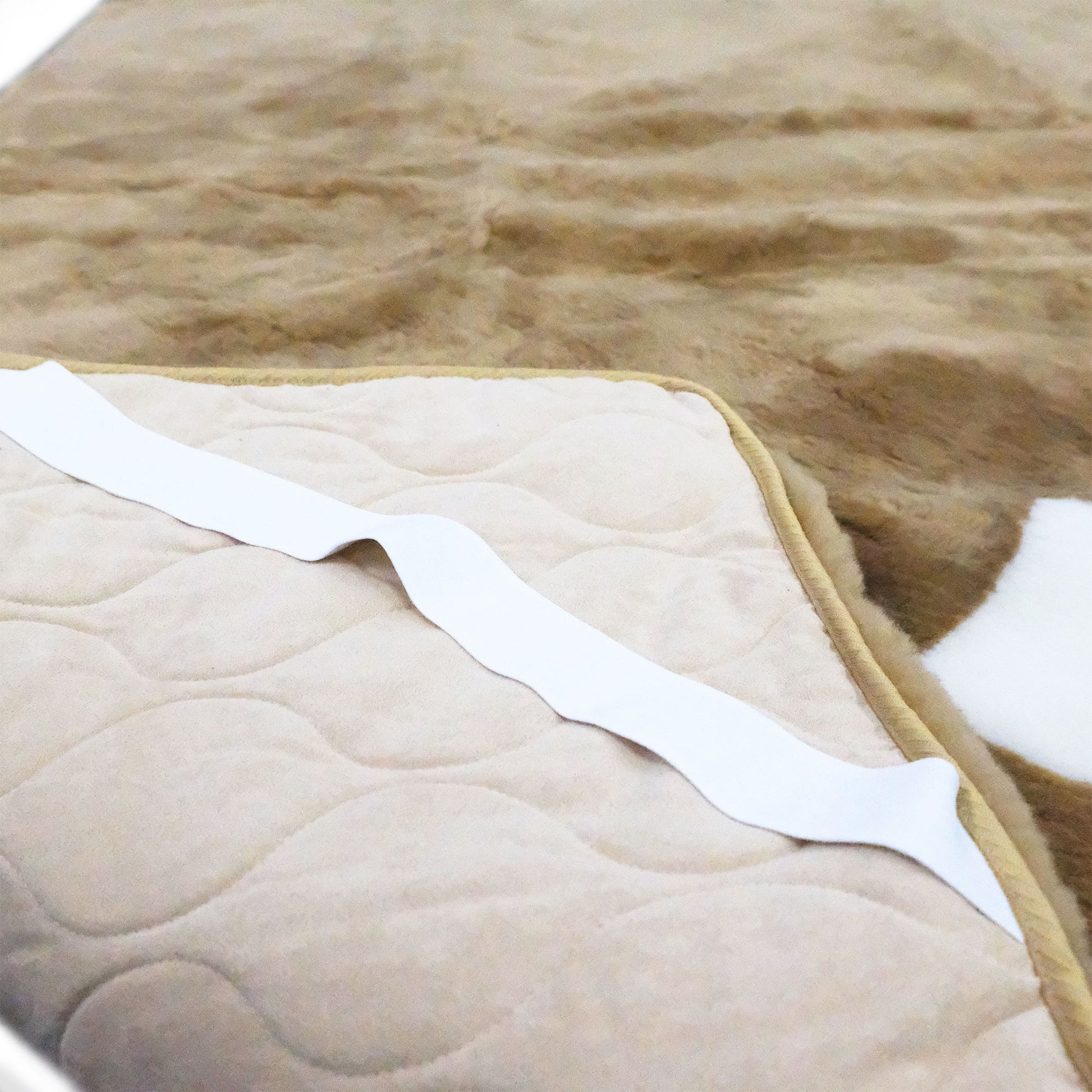 Cream quilted wool mattress topper with white binding, angled flat lay view. - Yellow Earth Australia