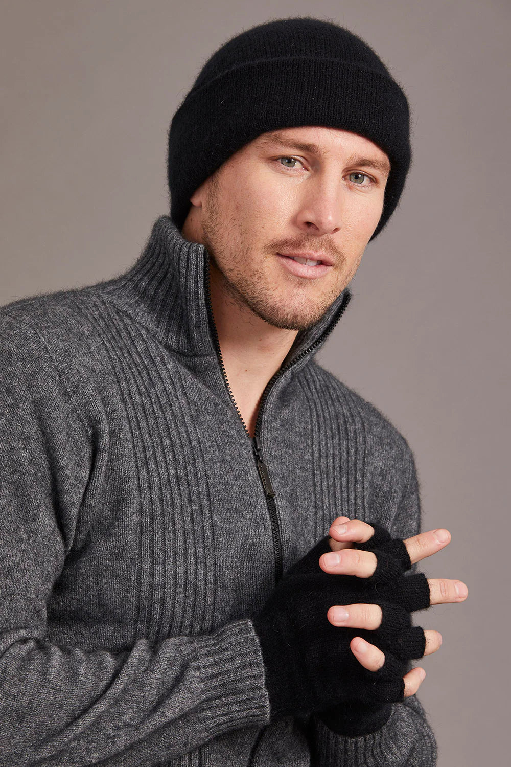 Man wearing black wool beanie and charcoal fingerless gloves against neutral background. - Yellow Earth Australia