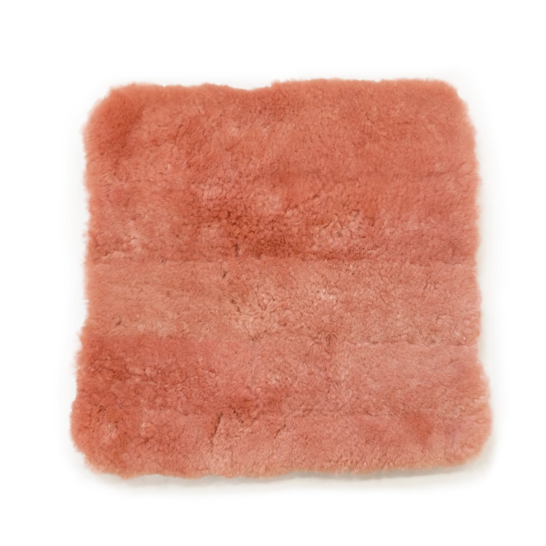 Soft peachy-pink sheepskin rug with fluffy wool texture, top-down view. - Yellow Earth Australia