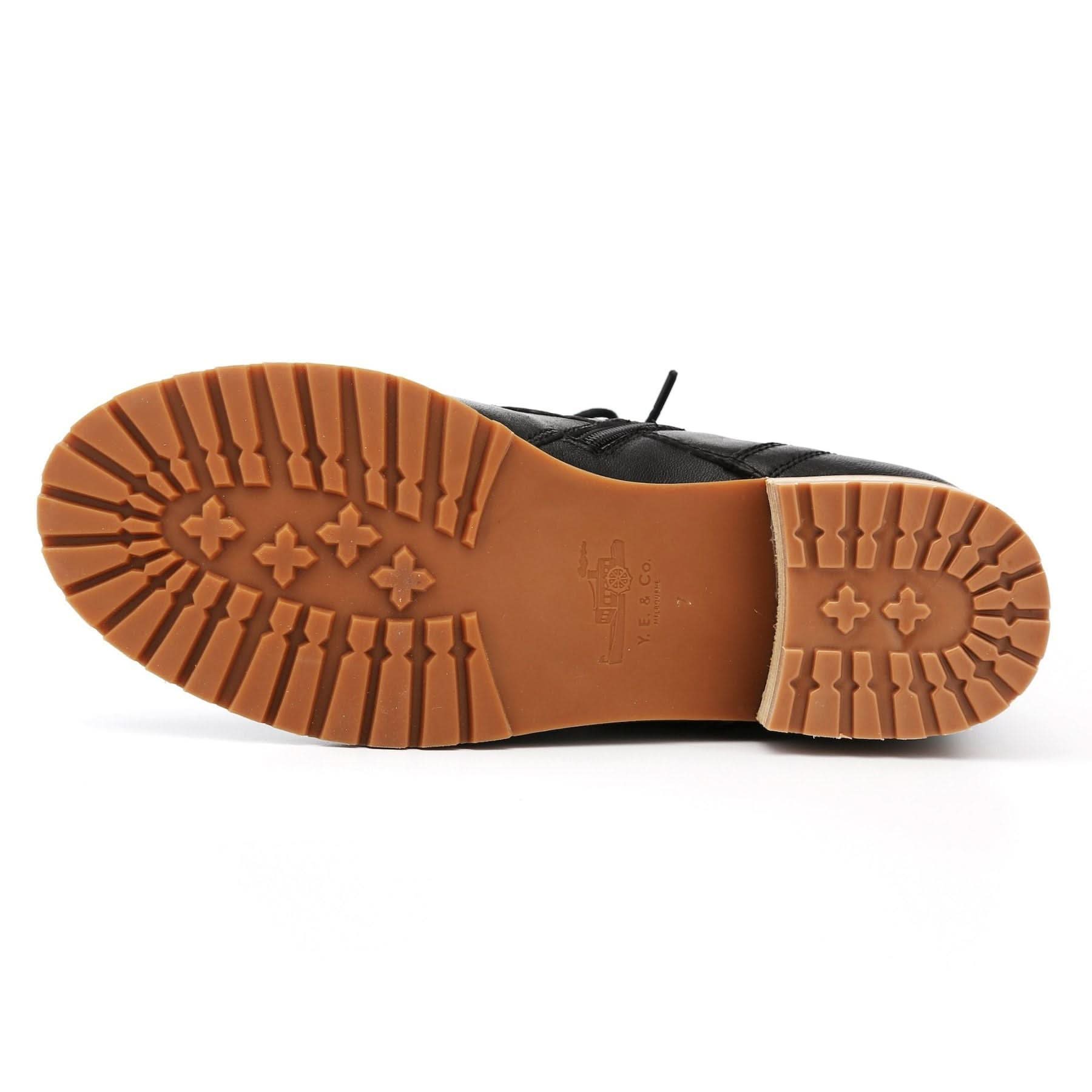 Black leather lace-up boot with tan rubber sole, bottom view. - Yellow Earth Australia