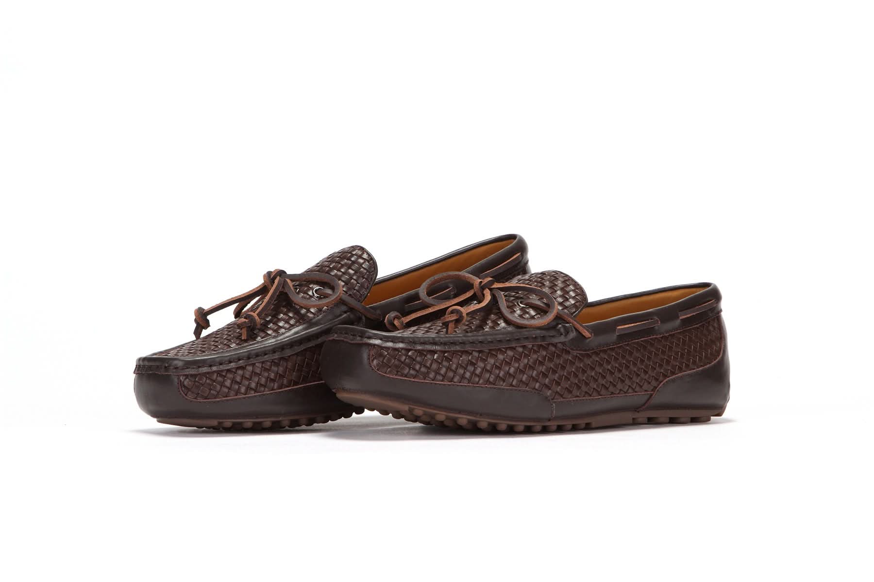 Pair of brown woven leather moccasins with laces and rubber sole on white background