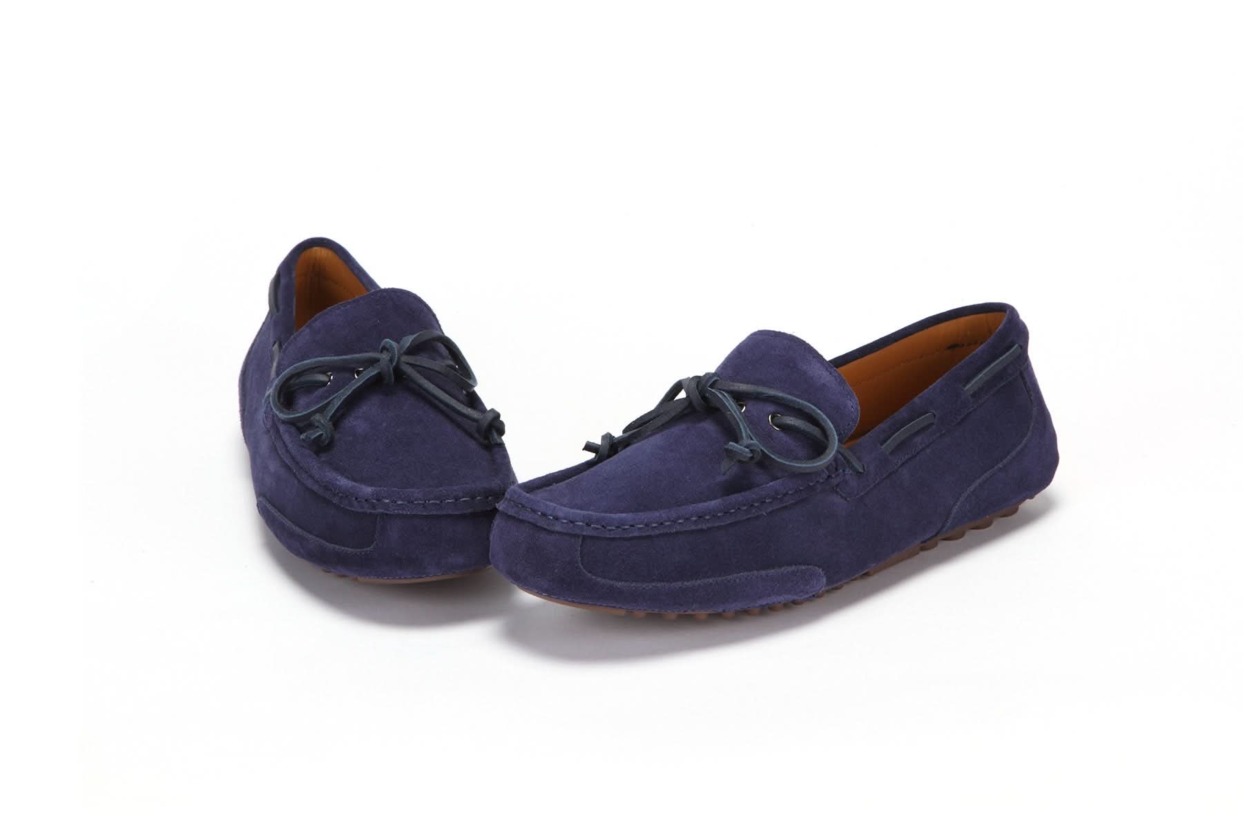 Men's navy blue suede moccasin slippers with bow detail on white background