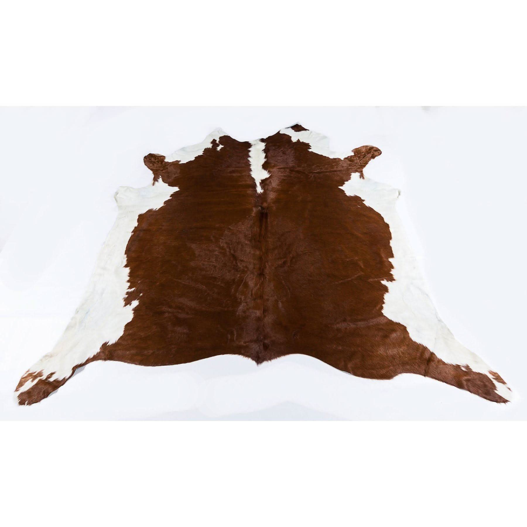 Brown and white cowhide rug displayed flat on white background. - Yellow Earth Australia