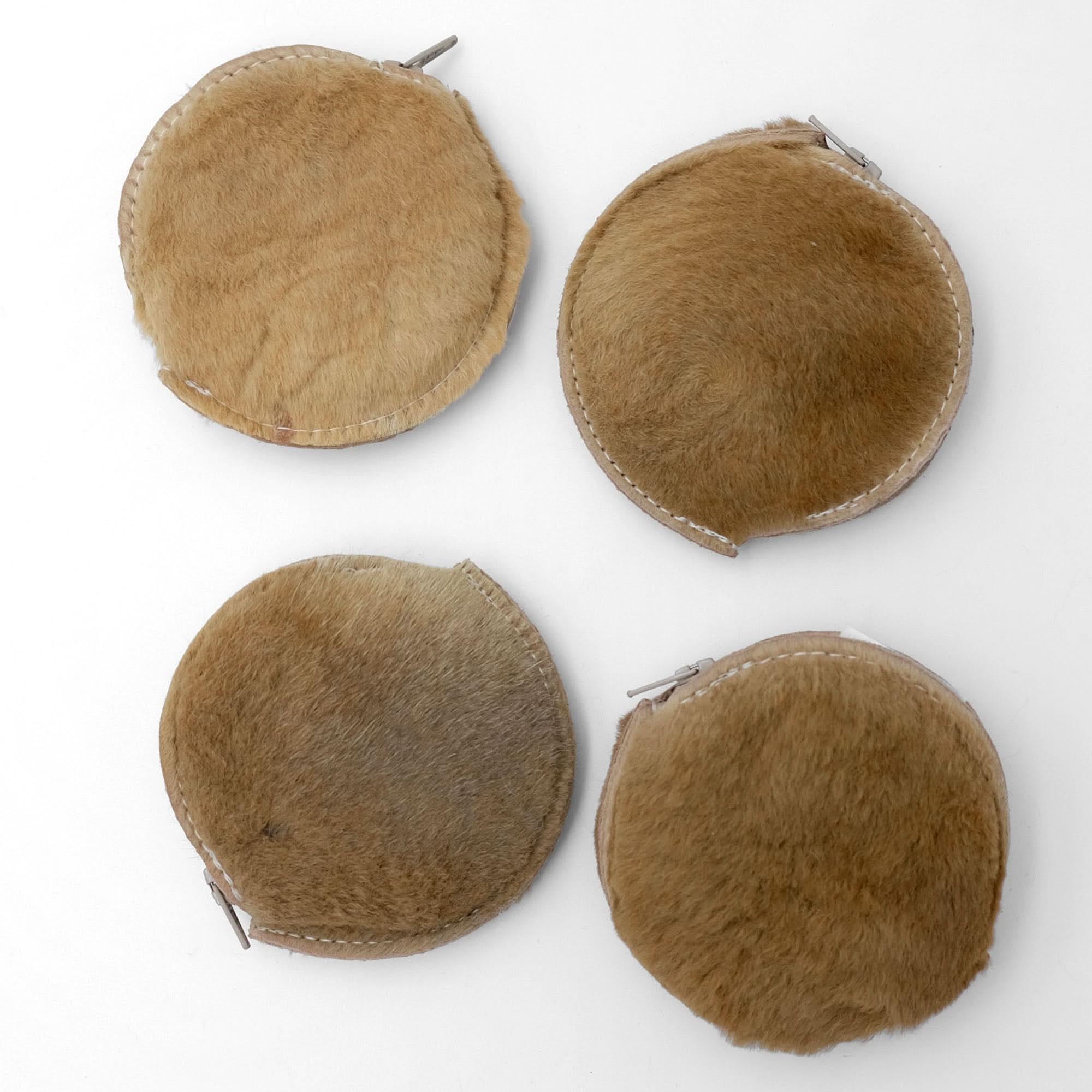 Four round sheepskin coin purses in natural tan with whipstitched edges, top view. - Yellow Earth Australia