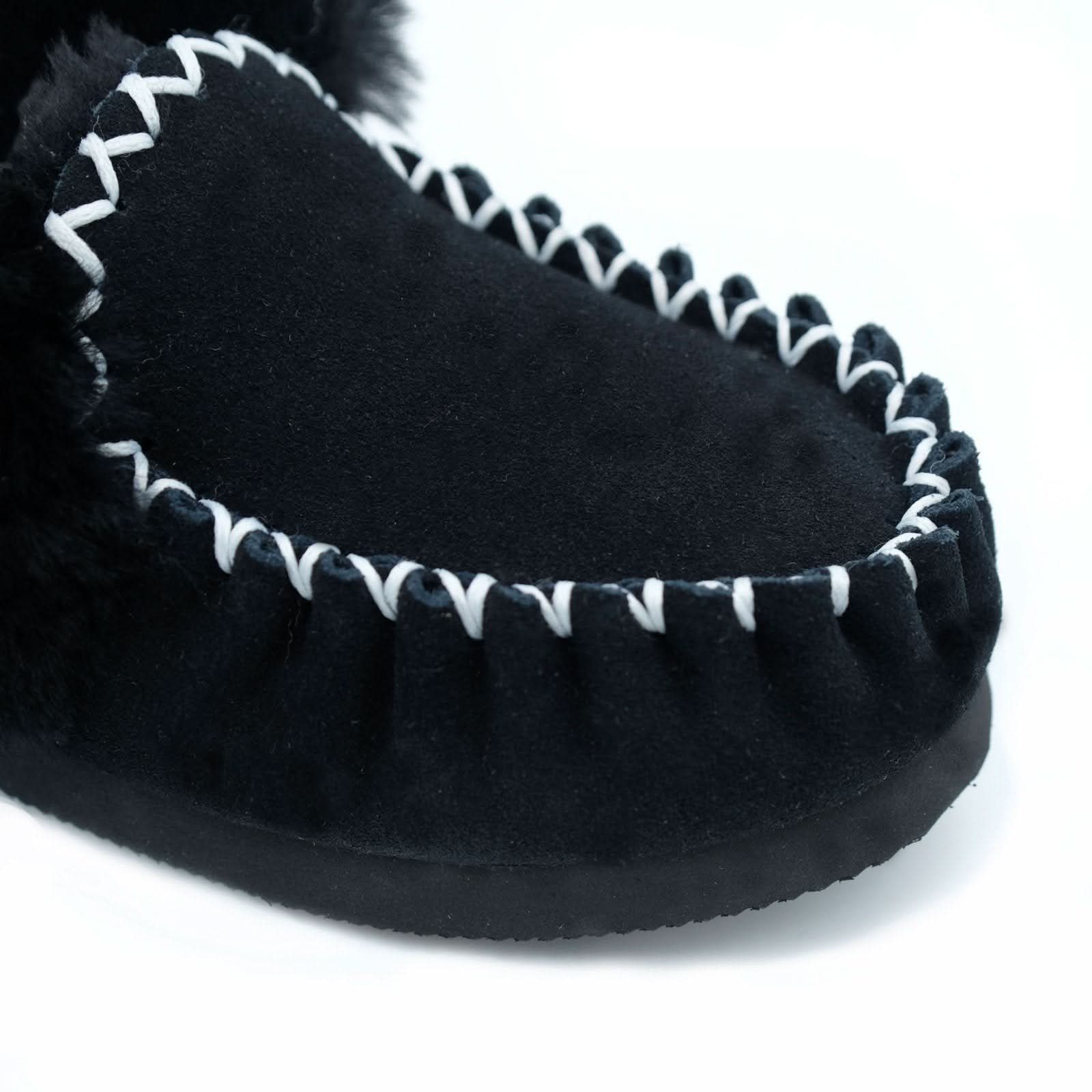 Black sheepskin slipper with white whipstitched edging, angled sole view. - Yellow Earth Australia