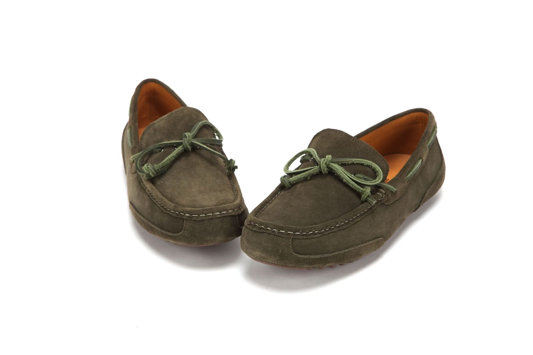 Pair of olive green suede moccasin slippers with bow detail on a white background