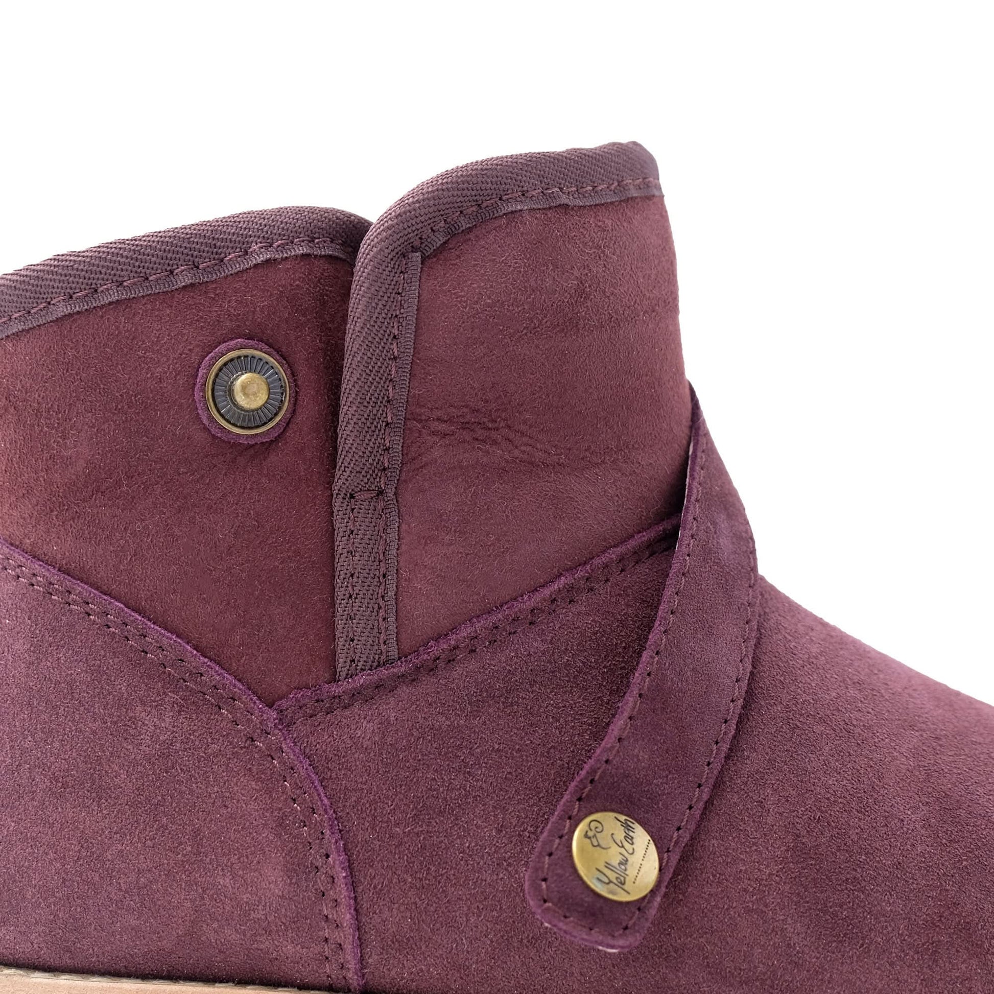 Close-up of a purple suede sheepskin boot with brass button details