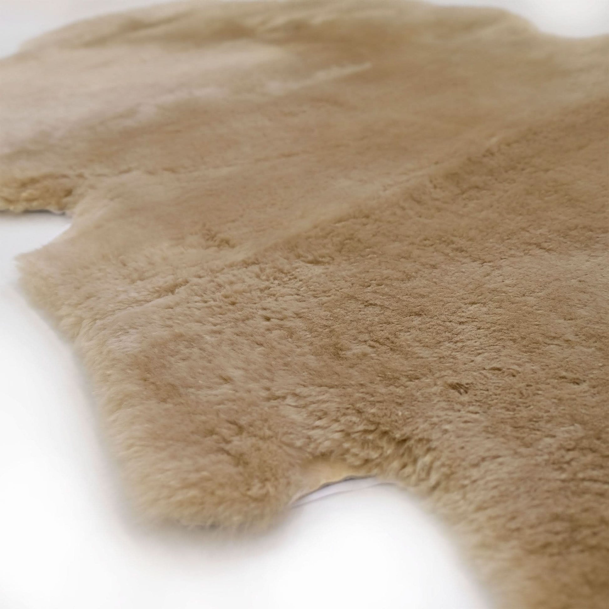 Close-up view of a natural beige sheepskin rug with soft wool texture. - Yellow Earth Australia