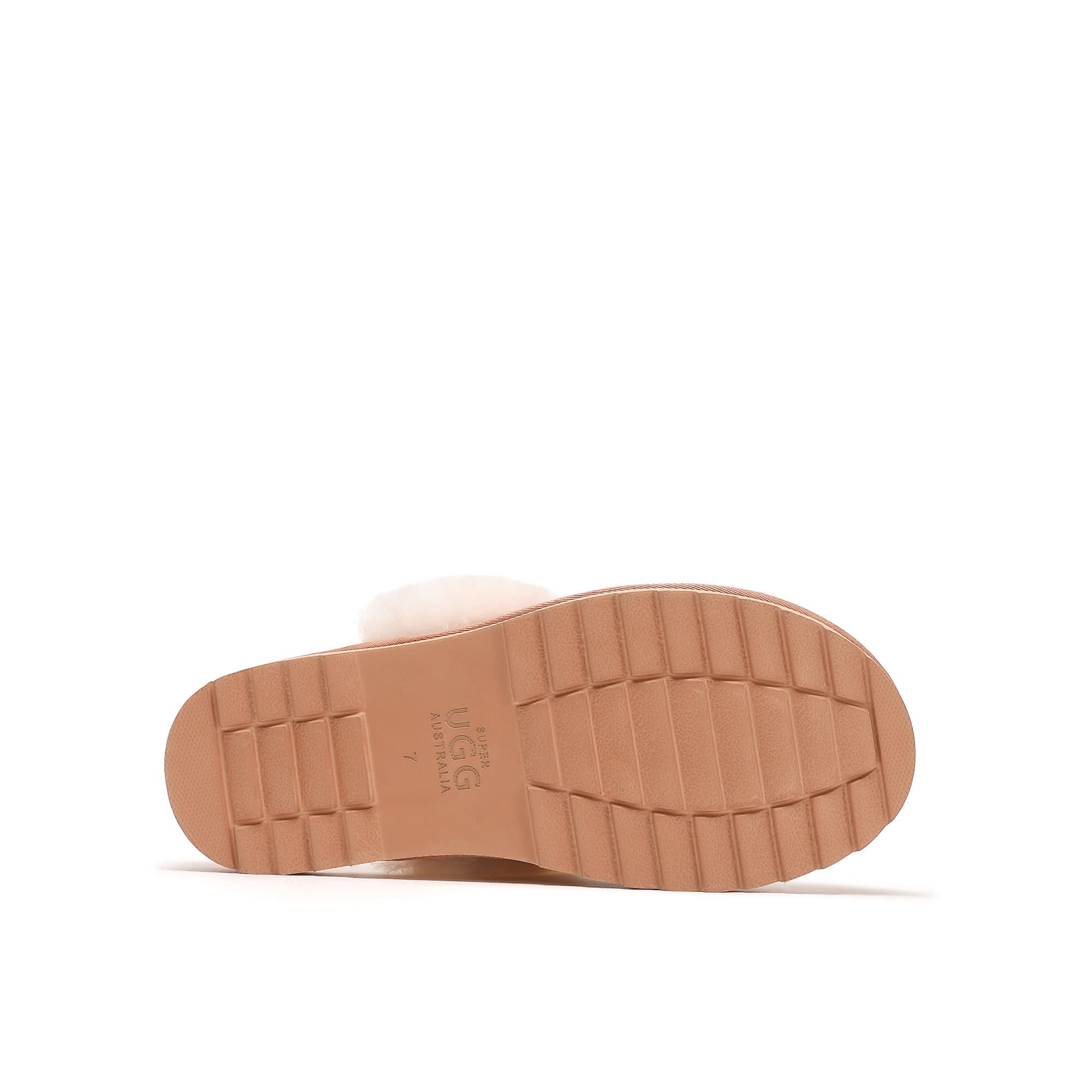 Tan rubber sole of a women's sheepskin slipper, textured tread, side view