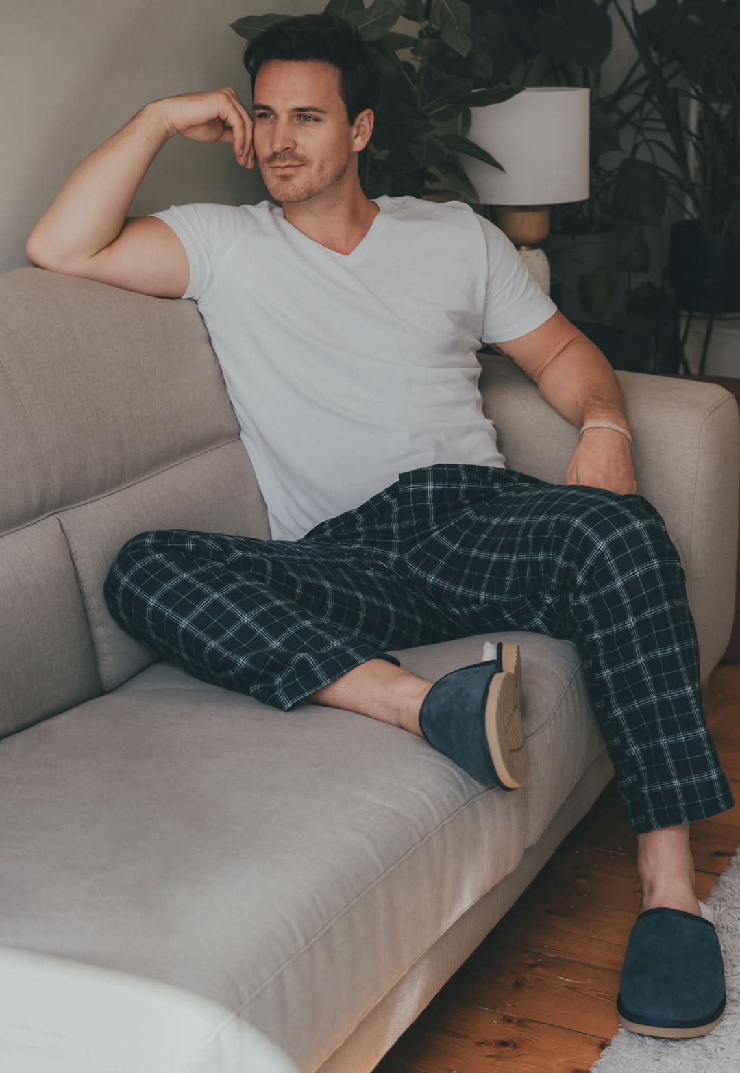 Man wearing navy plaid wool pajama pants on beige couch, front view. - Yellow Earth Australia