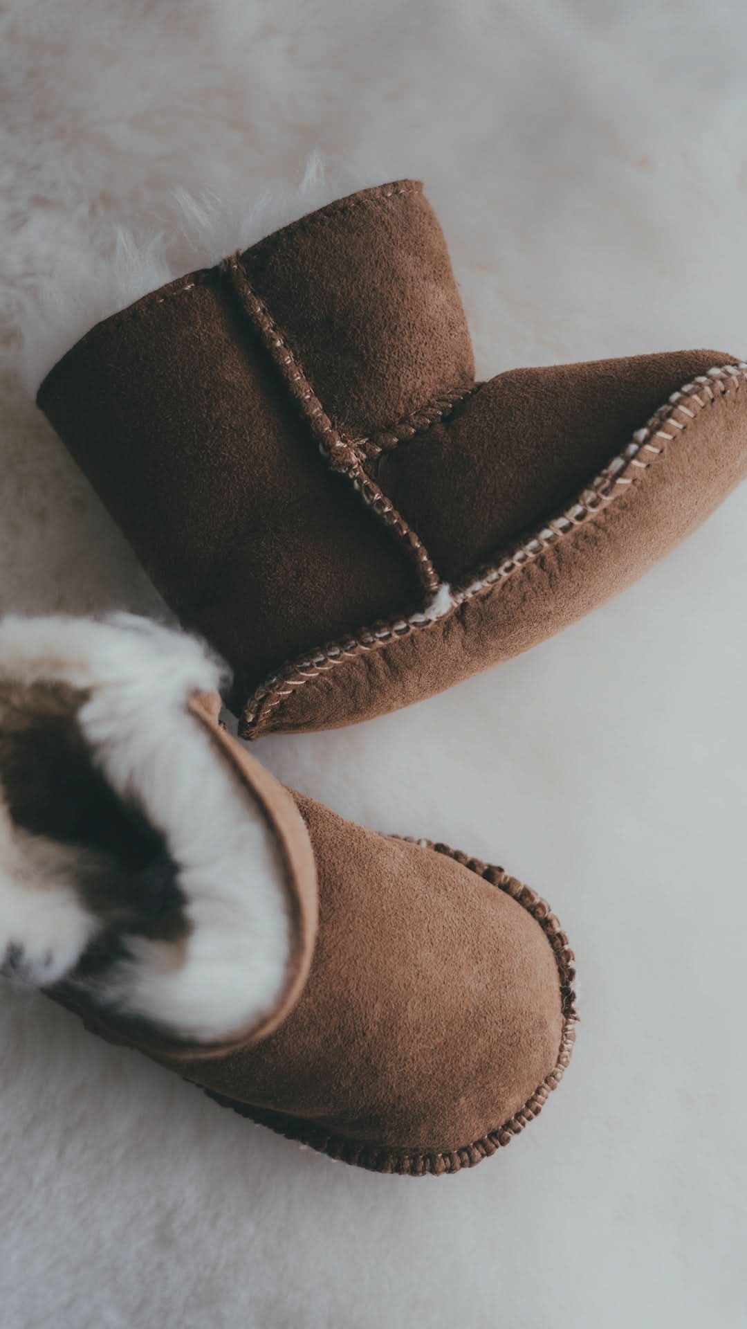 Pair of tan sheepskin boots with fluffy wool lining on white fur background. - Yellow Earth Australia