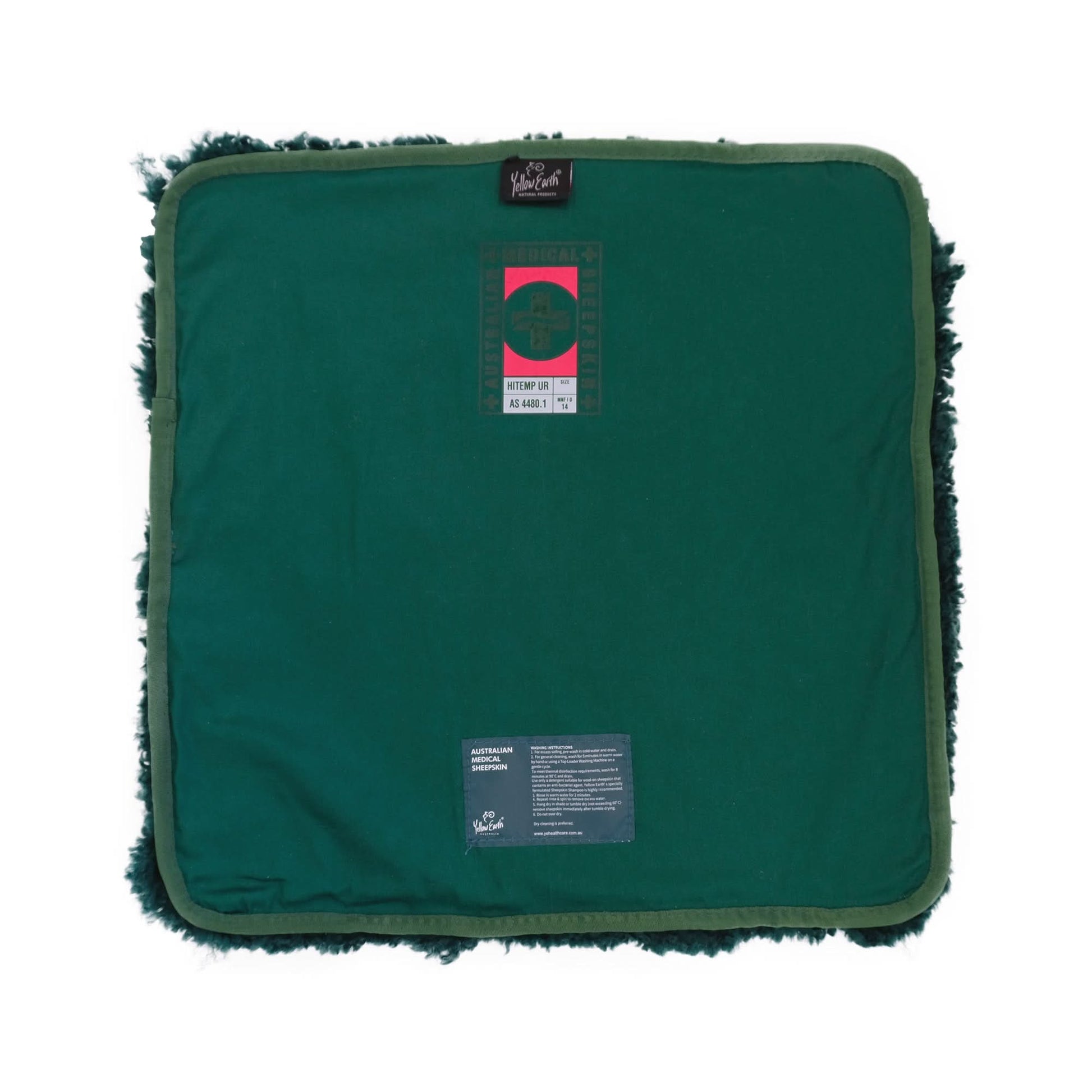 Green sheepskin seat pad with dark wool fringe, viewed from back showing care label tags. - Yellow Earth Australia
