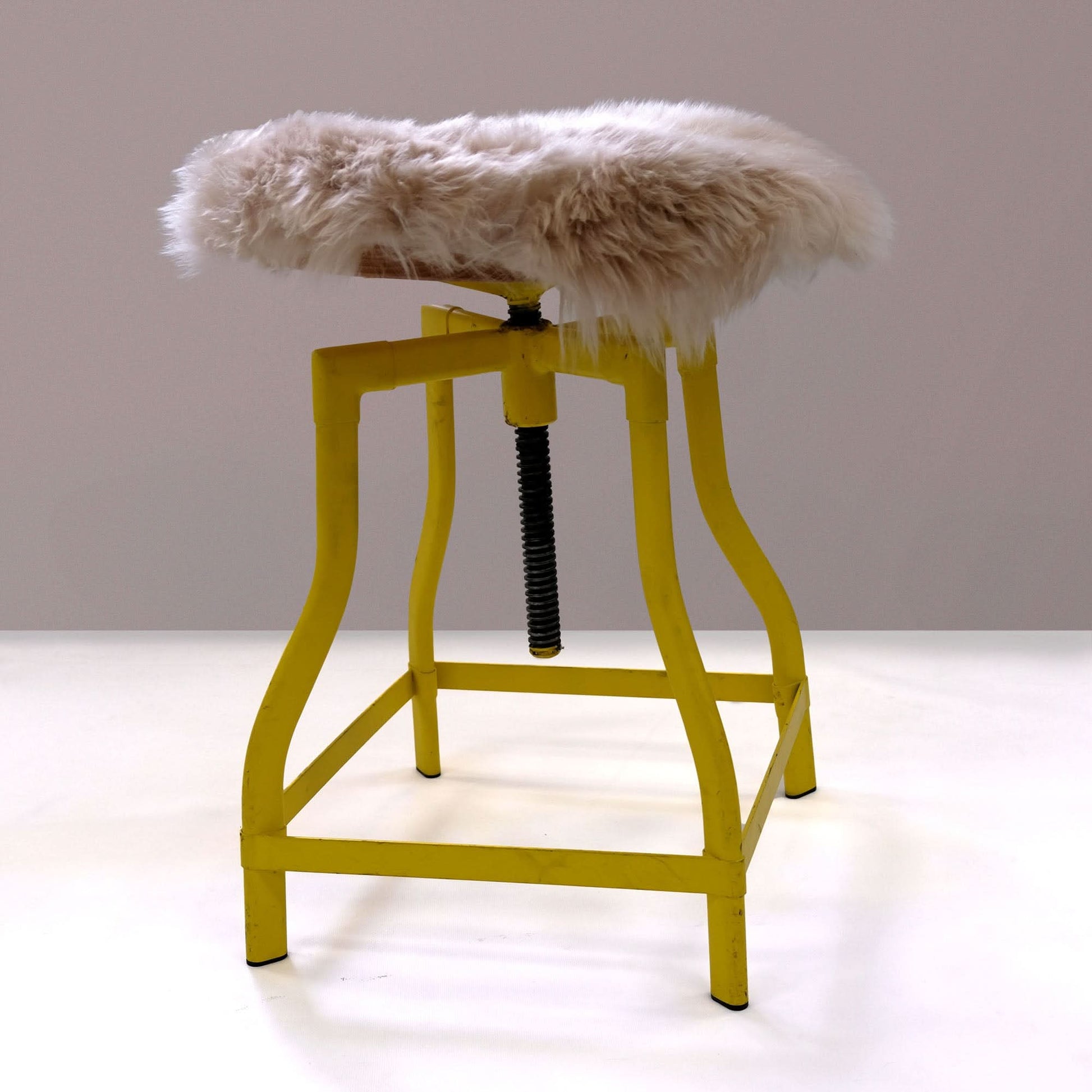 Yellow adjustable bar stool with white sheepskin seat pad, front angle view. - Yellow Earth Australia