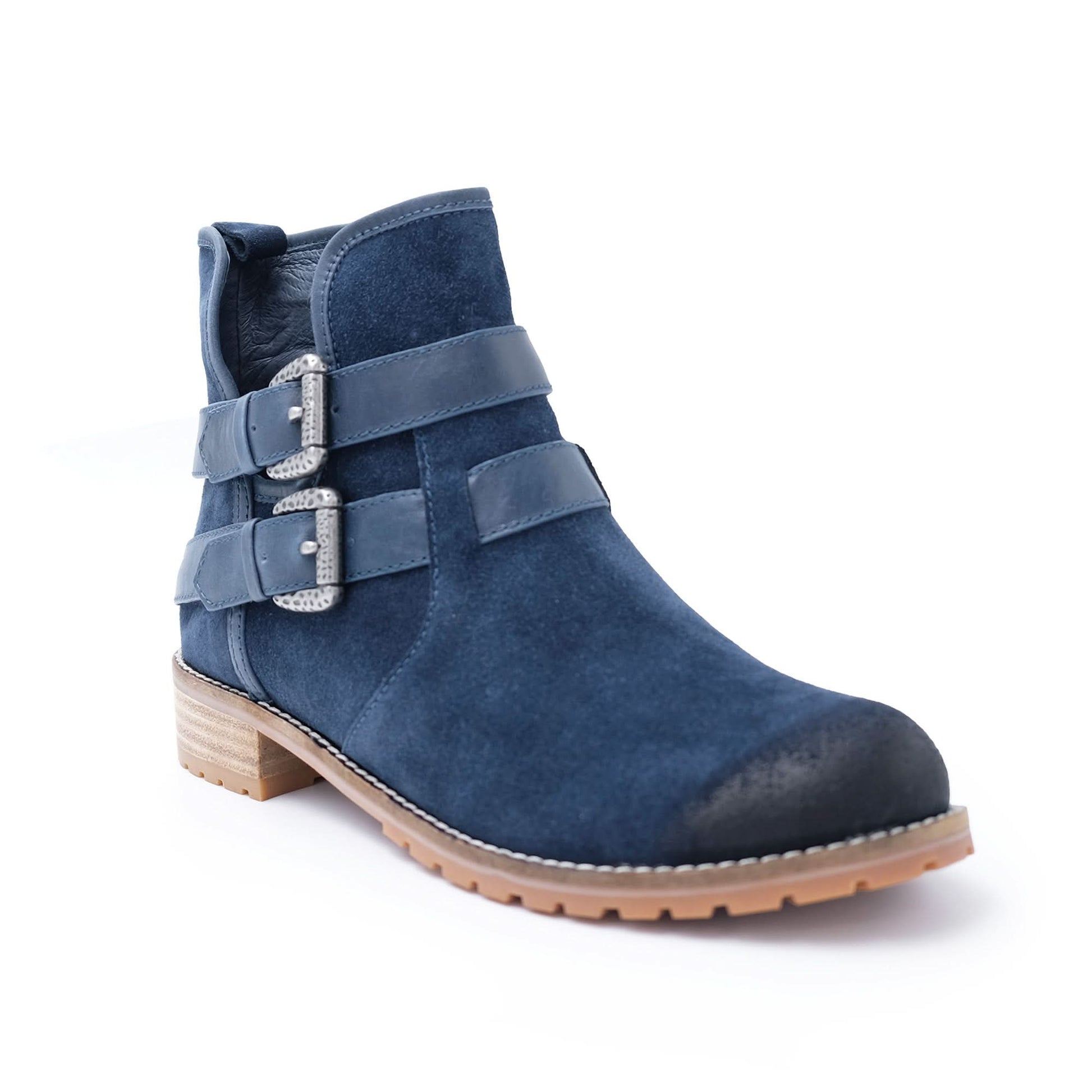 Navy blue suede ankle boot with decorative double straps, silver buckles, and tan sole